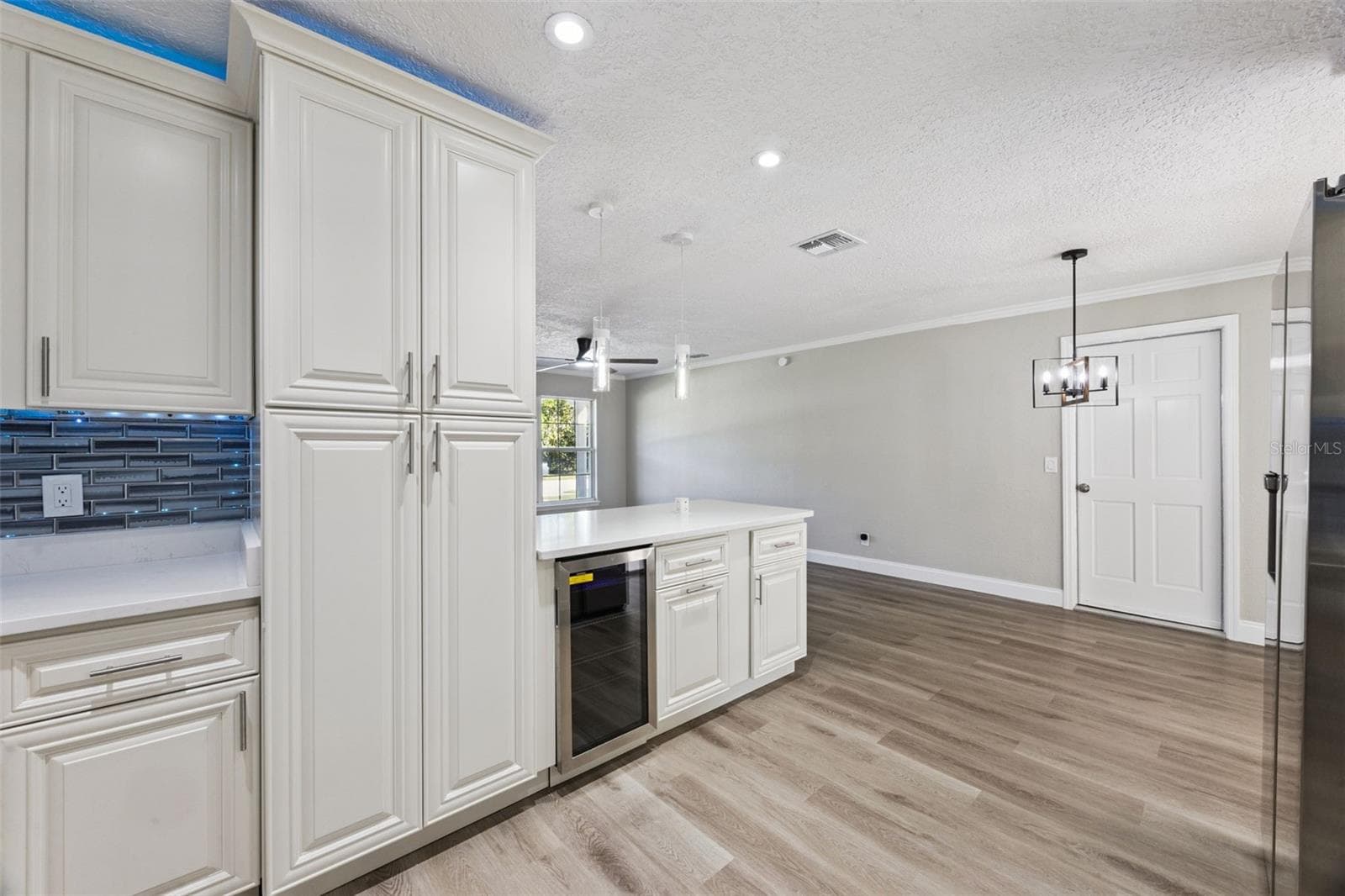 Kitchen Pantry & Wine Bar: Kitchen storage area featuring tall pantry cabinetry, white quartz countertops, glass pendant lighting, and a built-in beverage cooler - 720 GEORGIA AVE, LONGWOOD