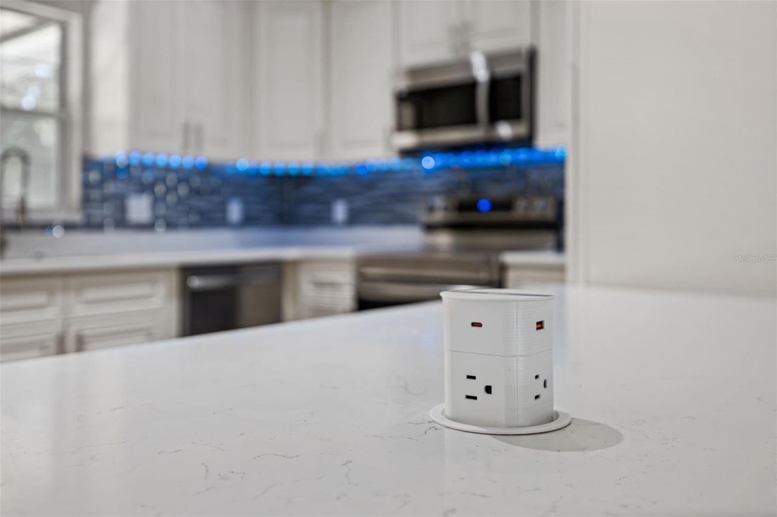 Pop-Up Countertop Outlet: Modern kitchen feature highlighting a pop-up island power hub with standard outlets and USB charging ports. - 720 GEORGIA AVE, LONGWOOD