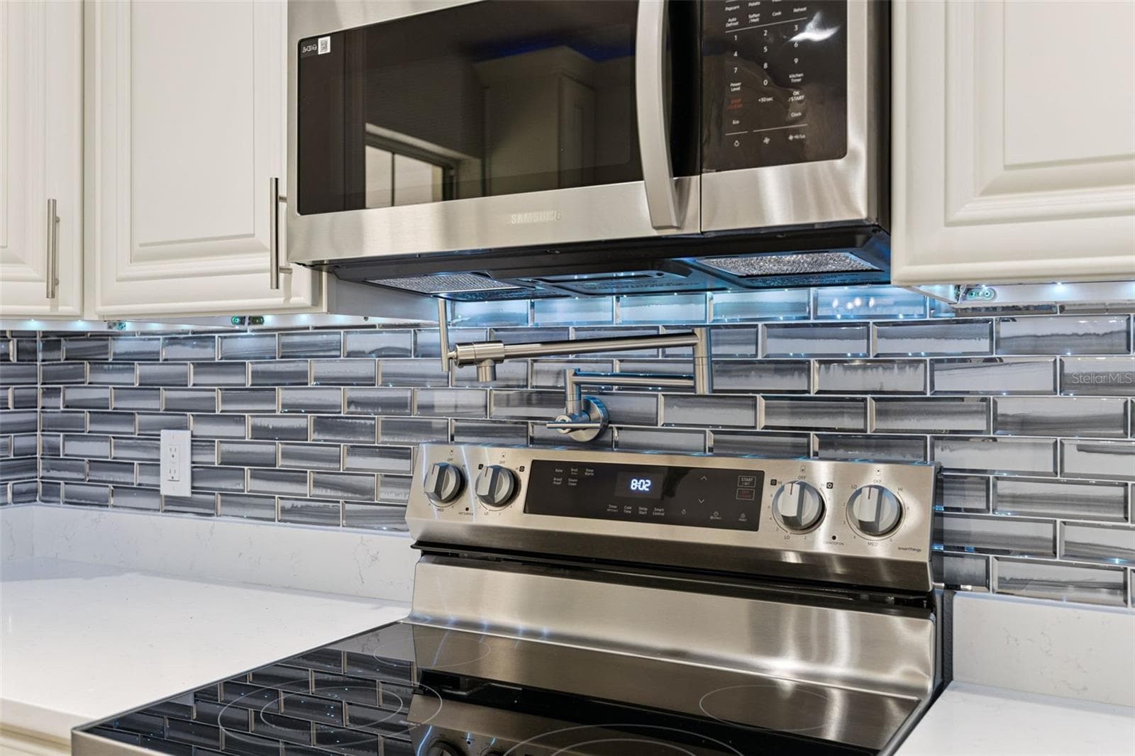 Wall-Mounted Pot Filler: Gourmet detail featuring a stainless steel wall-mounted pot filler over the stove set against a tile backsplash. - 720 GEORGIA AVE, LONGWOOD