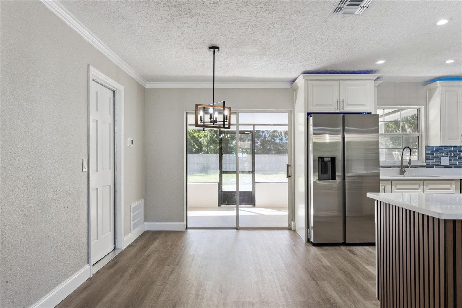 Dining Nook & Patio Access: Light-filled dining area featuring a modern lantern chandelier, sliding glass door access to the screened patio, and view into the kitchen. - 720 GEORGIA AVE, LONGWOOD