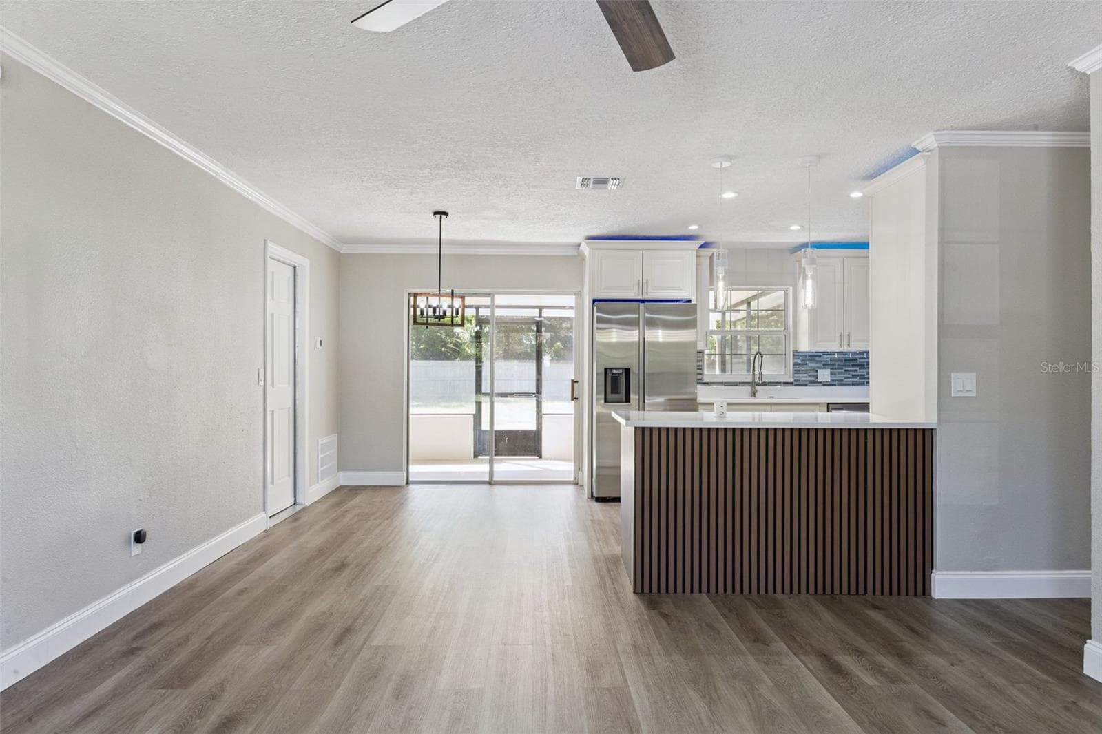 Dining & Kitchen Transition: Seamless transition between dining and kitchen spaces with pendant lighting, sliding patio doors, and slatted island accents. - 720 GEORGIA AVE, LONGWOOD