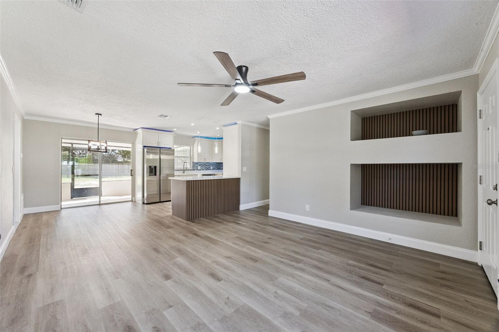 Open-Concept Living Main Space: Bright open-concept floor plan showcasing built-in accent wall niches, durable plank flooring, and smooth flow into the kitchen and dining area - 720 GEORGIA AVE, LONGWOOD