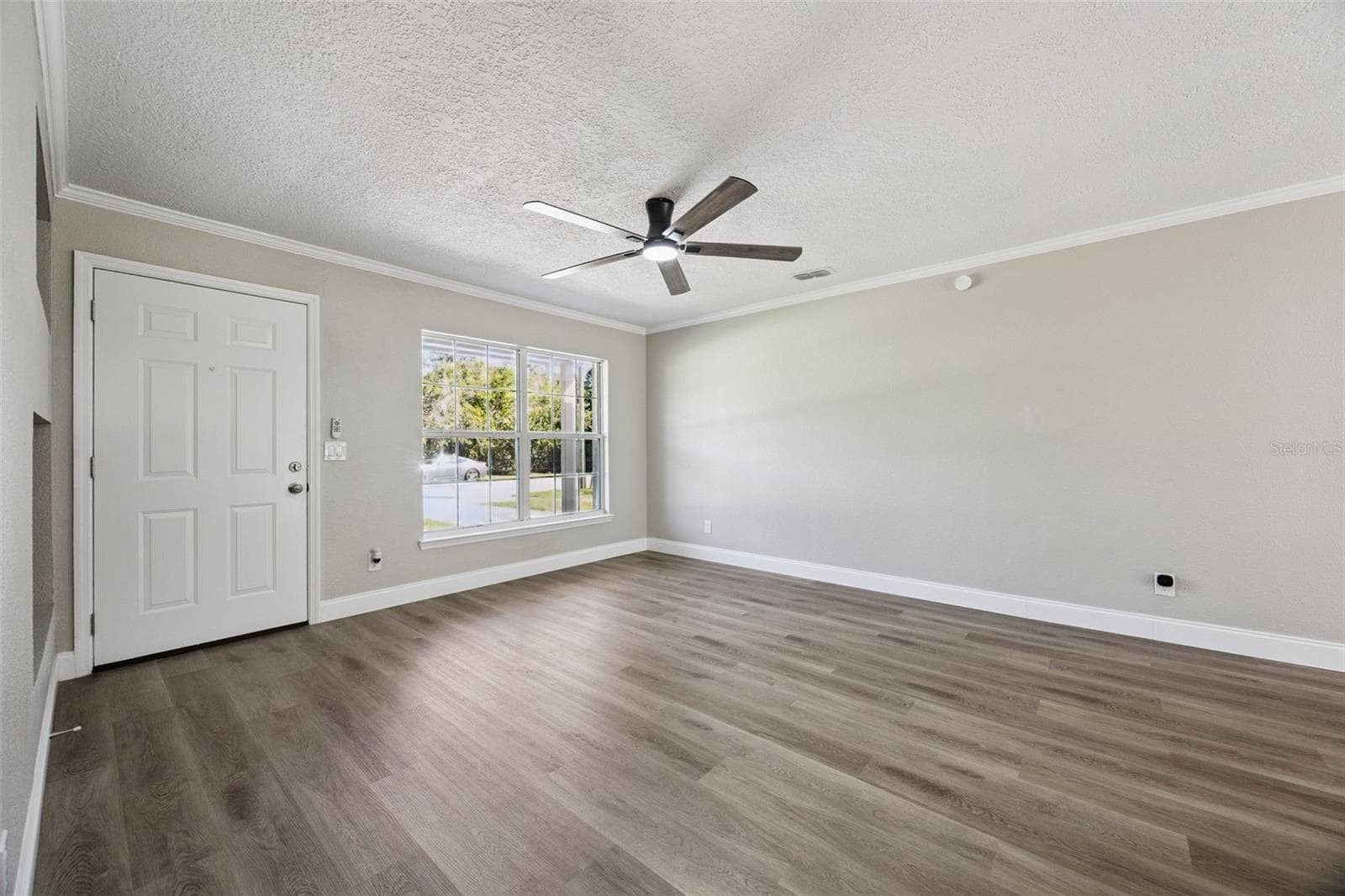 Foyer & Living Area: Welcoming front foyer and open living room featuring luxury vinyl plank flooring, neutral paint, crown molding, and a modern ceiling fan - 720 GEORGIA AVE, LONGWOOD