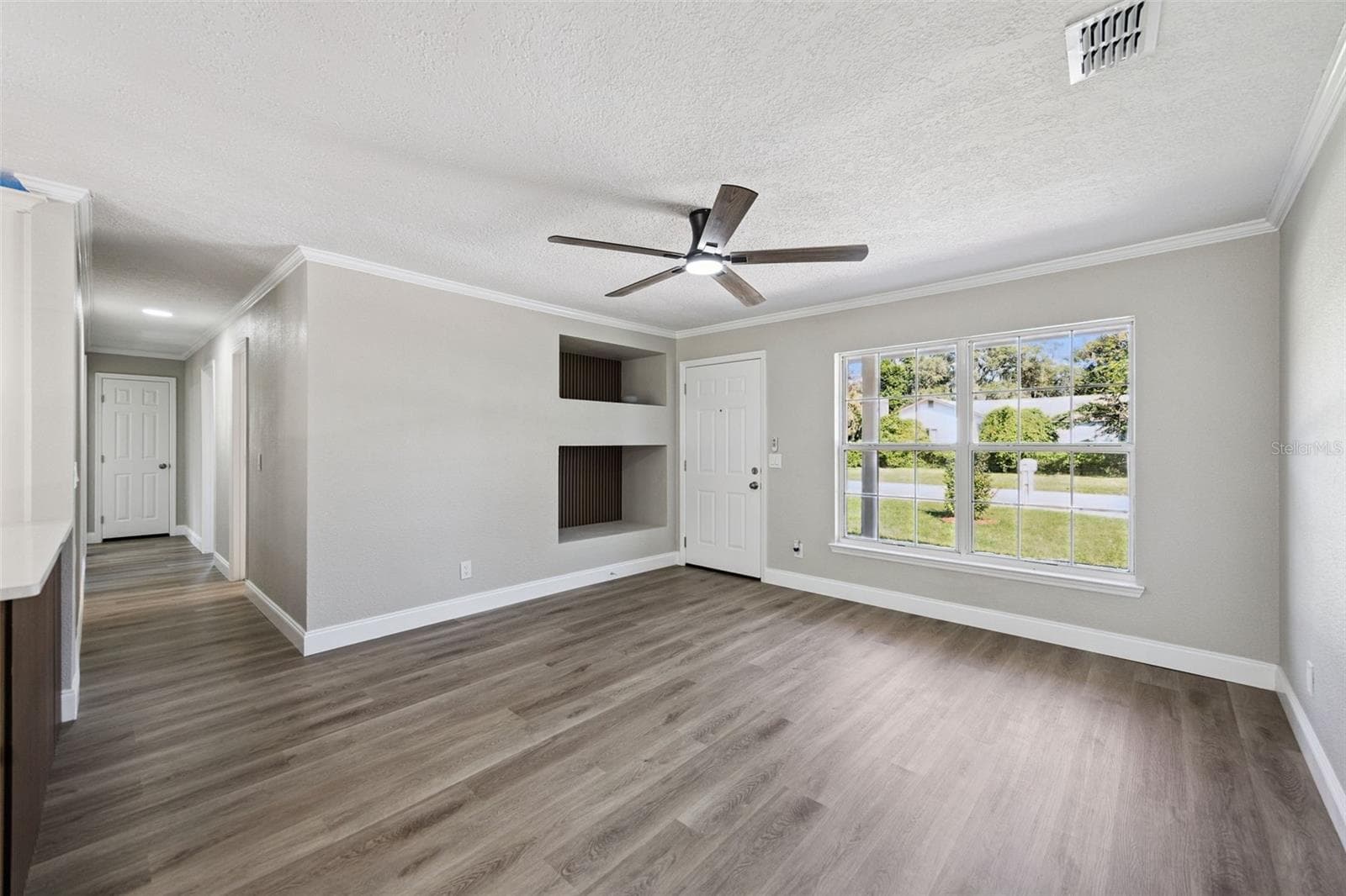 Living Room & Recessed Niches: Spacious main living room highlighting built-in wall display niches, modern ceiling fan, large front window, and durable vinyl plank flooring - 720 GEORGIA AVE, LONGWOOD