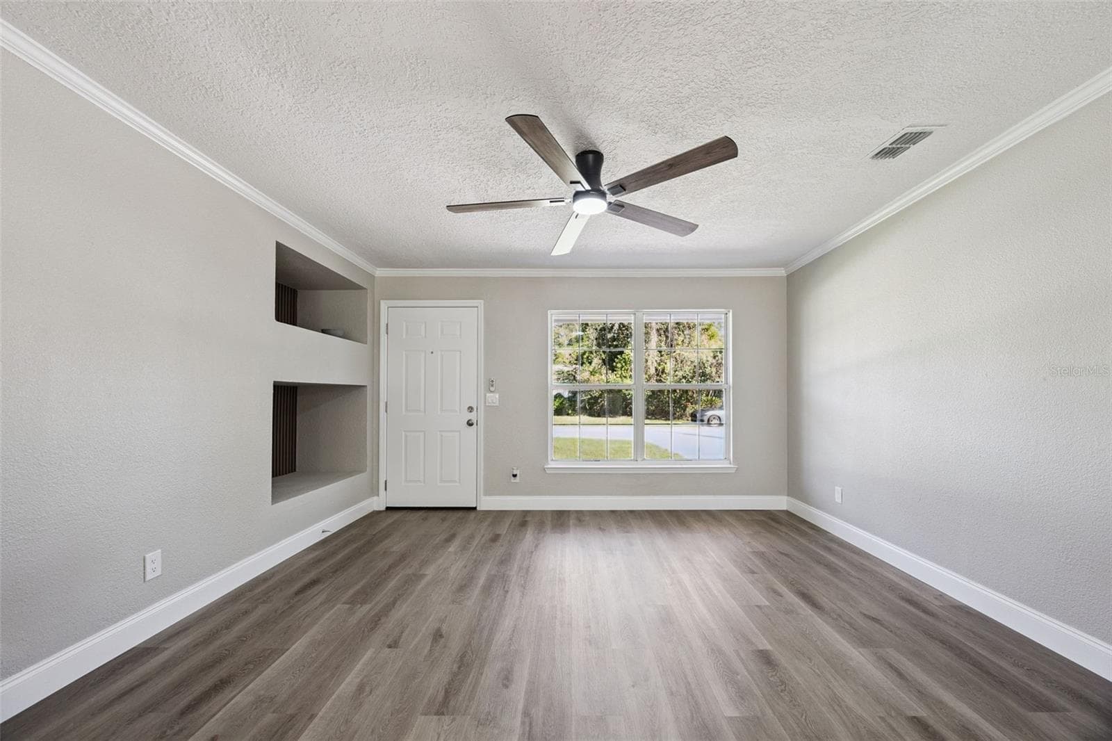 Front Living Space: Welcoming living area filled with natural light from large double windows, complete with smooth ceiling finishes, crown molding, and a modern fan - 720 GEORGIA AVE, LONGWOOD