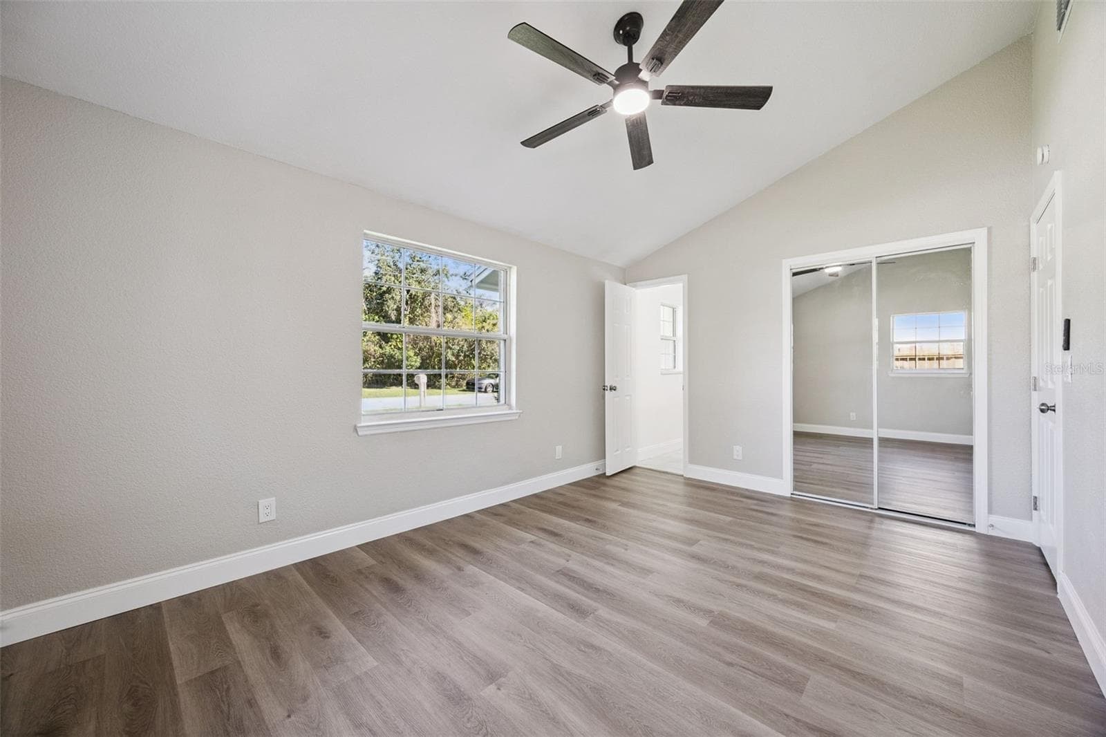 Primary Suite Alternate View: Generous primary bedroom layout highlighting high ceilings, neutral wall tones, bright window view, and built-in closet storage. - 720 GEORGIA AVE, LONGWOOD