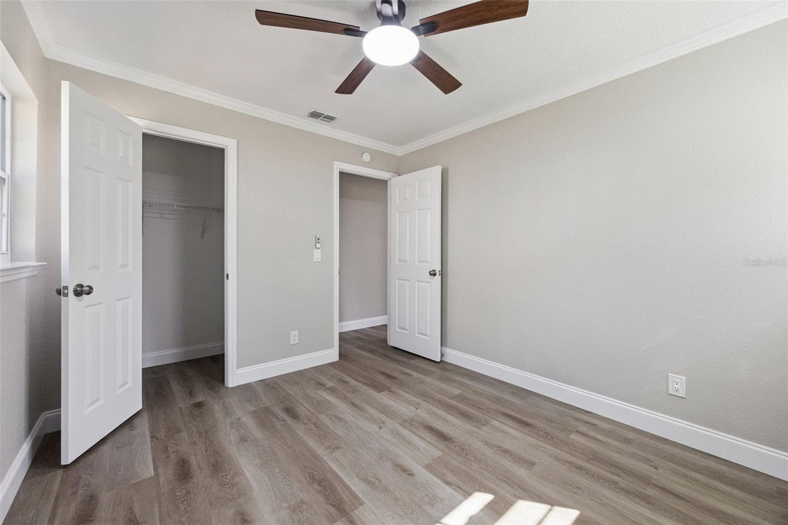 Guest Bedroom & Closet: Cozy guest bedroom with wood-look vinyl plank flooring, neutral grey paint, ceiling fan, and an open walk-in closet. - 720 GEORGIA AVE, LONGWOOD