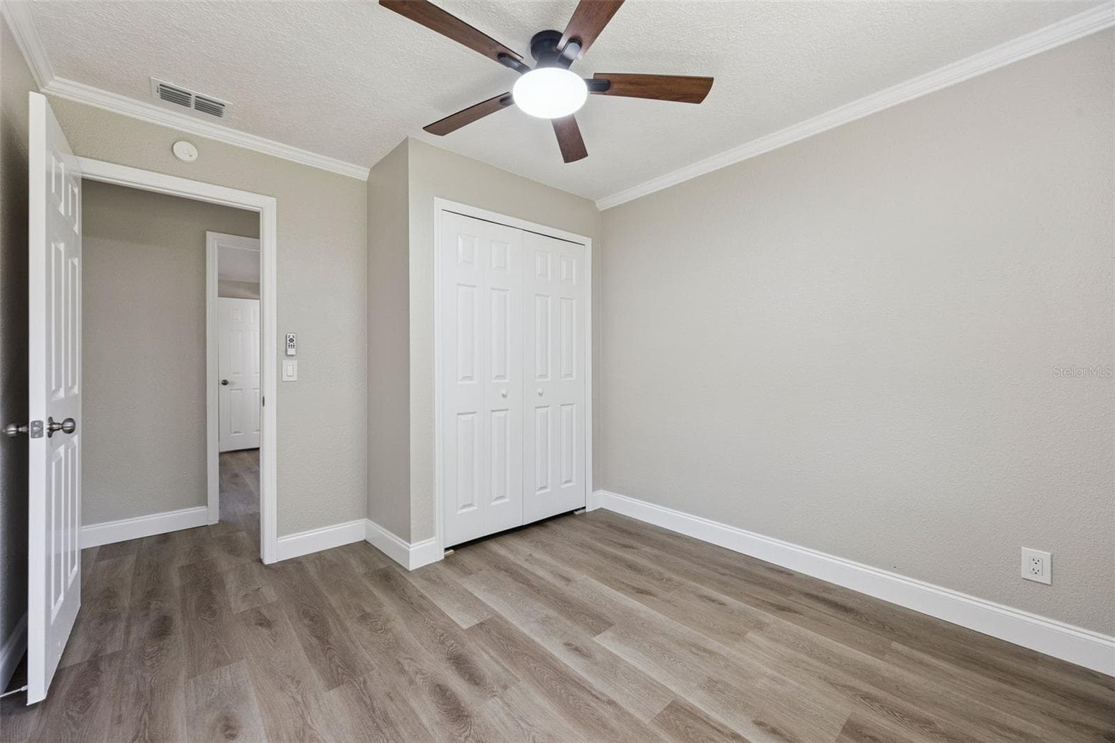Secondary Bedroom: Bright secondary bedroom featuring double bi-fold closet doors, modern ceiling fan, crown molding, and durable plank flooring - 720 GEORGIA AVE, LONGWOOD
