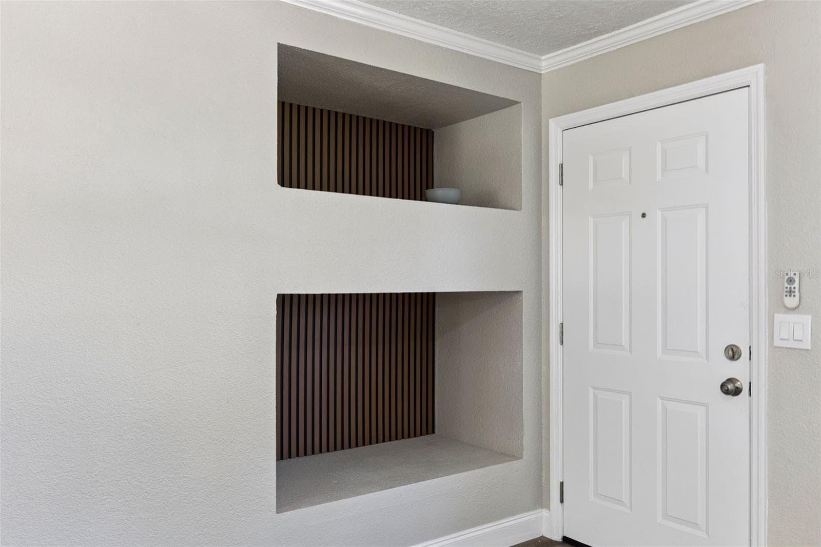 Foyer Architectural Niches: Entryway detail featuring dual built-in recessed display niches with decorative slatted wood backdrops. - 720 GEORGIA AVE, LONGWOOD