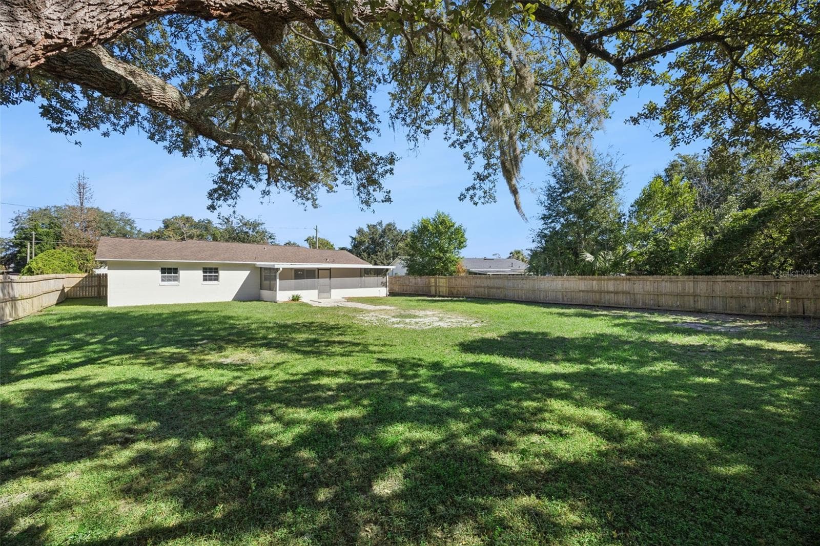 Lawn & Oak Canopy: Broad panoramic view of the lush, open backyard completely enclosed by wooden privacy fencing under a grand oak canopy - 720 GEORGIA AVE, LONGWOOD