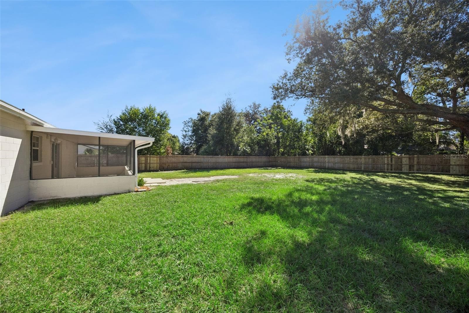 Rear Grounds & Shade Tree: Corner view of the rear property showcasing the sprawling green lawn, screened patio, and mature trees. - 720 GEORGIA AVE, LONGWOOD
