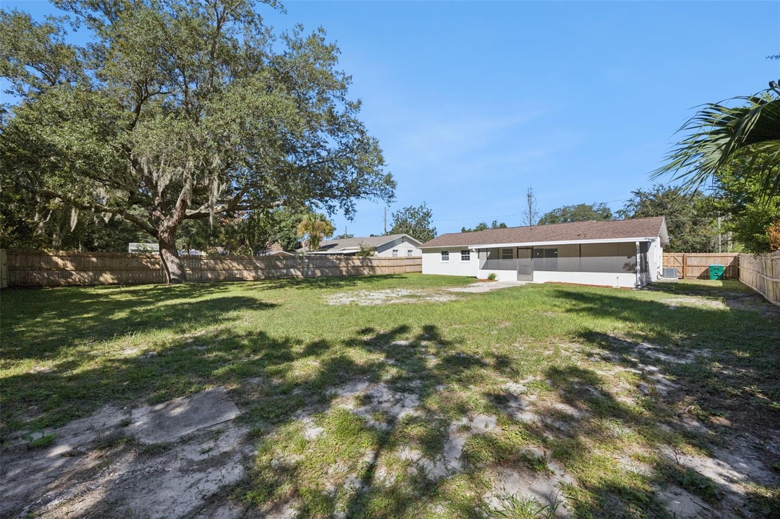 Yard Angle & Oak Canopy: Wide view of the fully fenced rear yard highlighting lush green grass and a magnificent shade oak. - 720 GEORGIA AVE, LONGWOOD
