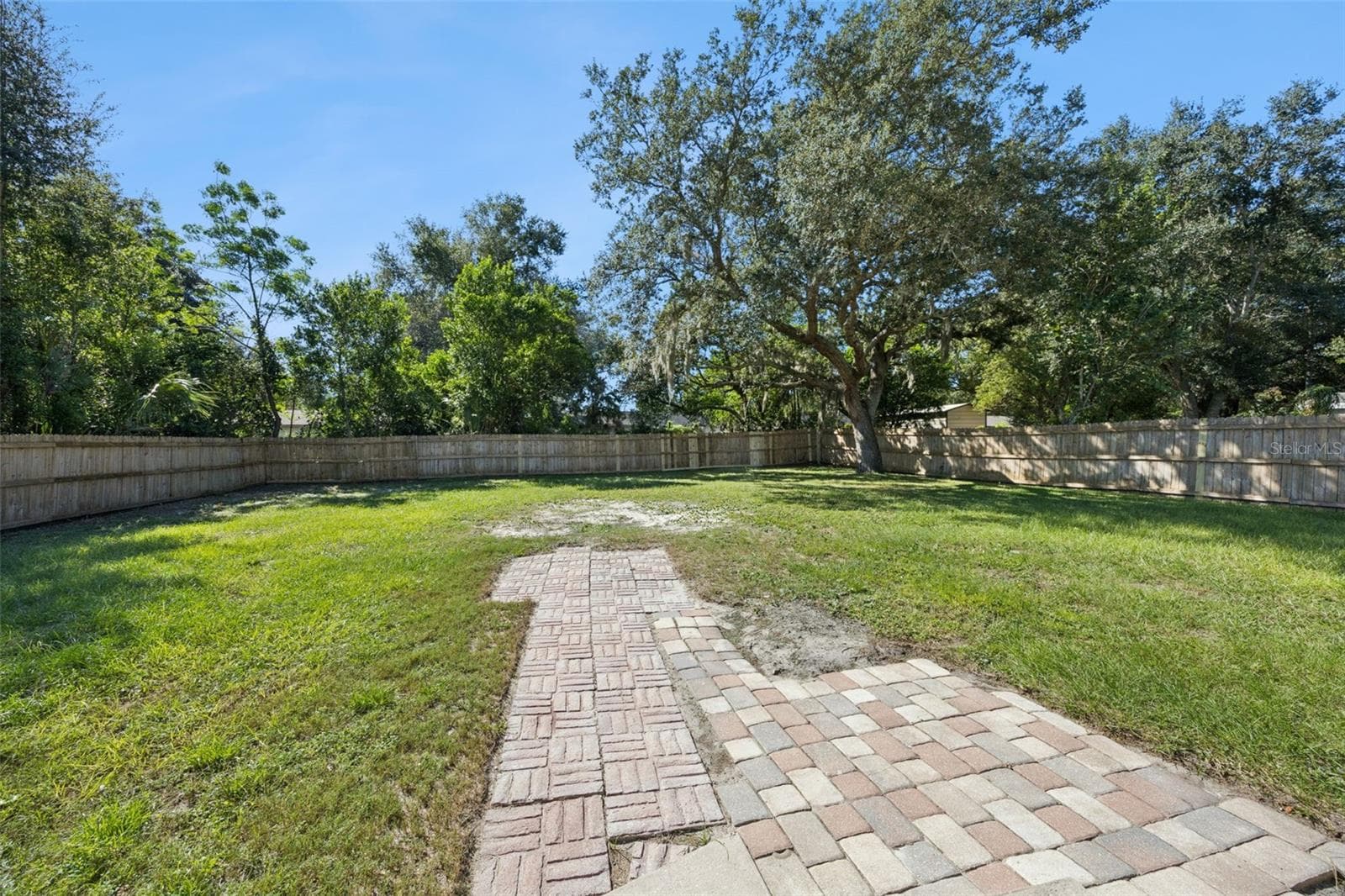 Paver Patio & Yard View: Close-up of the brick paver pathway leading out into the spacious, private backyard. - 720 GEORGIA AVE, LONGWOOD