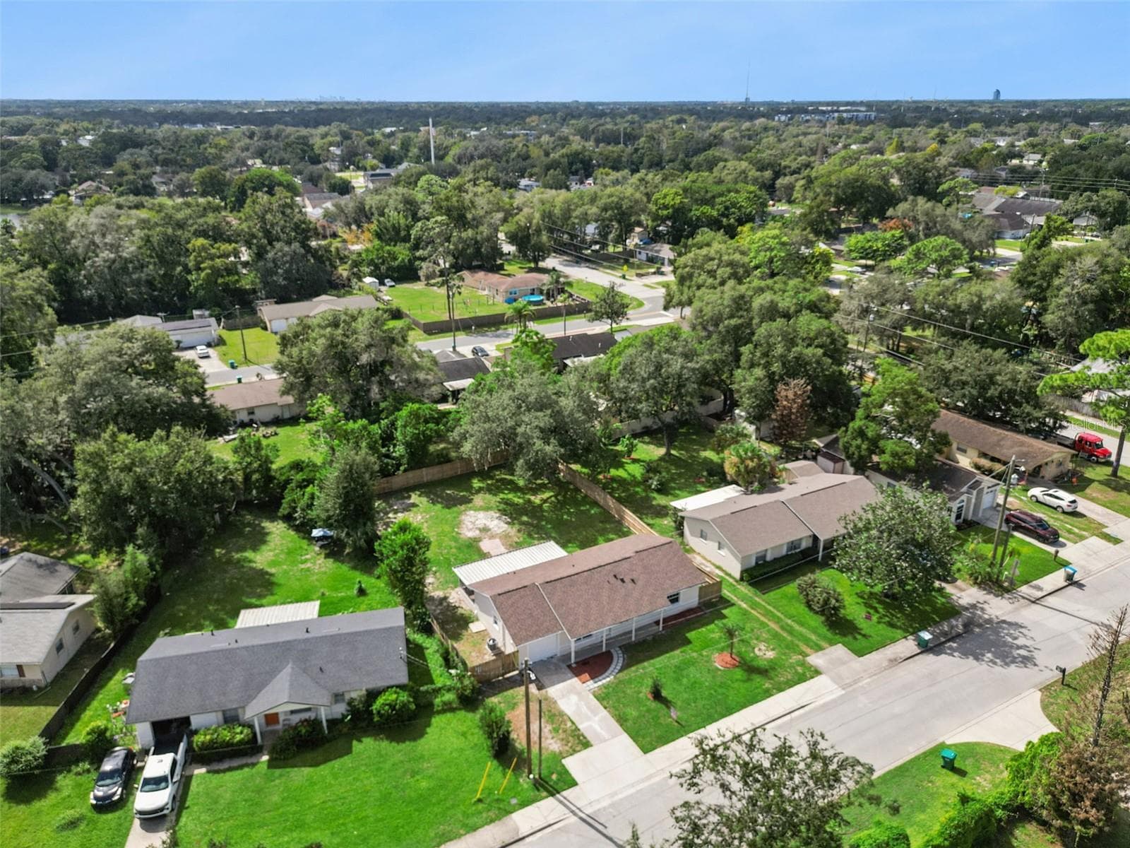 Aerial View of Property & Street: Elevated perspective displaying the home's front elevation, driveway, screened porch, and lush lot along a quiet residential street. - 720 GEORGIA AVE, LONGWOOD