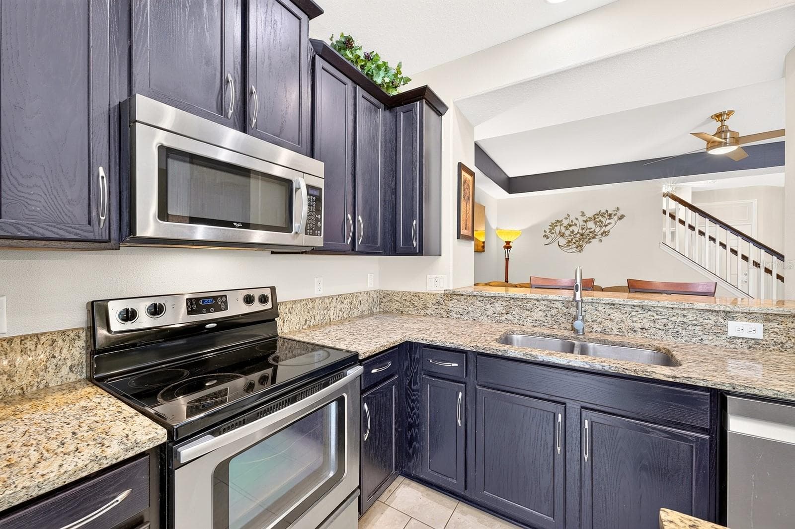 The nearby Kitchen is both stylish and functional, offering an abundance of 42-inch cabinetry, STONE COUNTERTOPS, a center island, STAINLESS STEEL APPLIANCES, including a NEWER DISHWASHER (2022), and a spacious breakfast bar. - 2109 VICTORIA GLEN DR, SANFORD