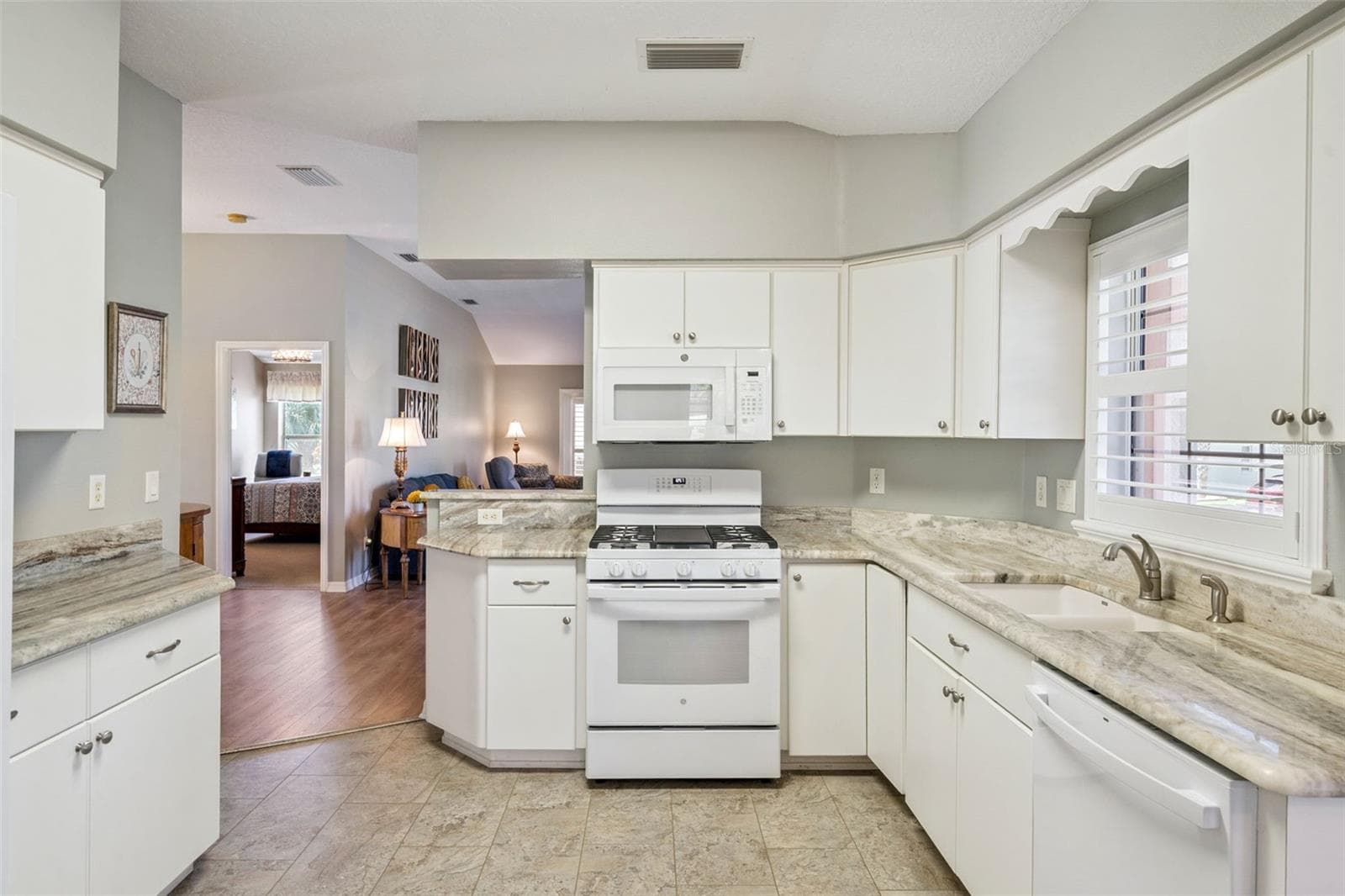 Kitchen with granite counters, white cabinetry and appliances from 2024. - 4900 CANOE CT, TAVARES