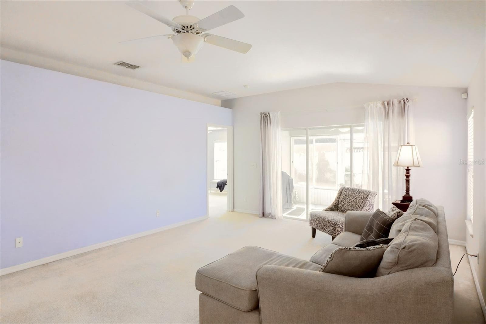 Triple sliding glass doors leading to the Florida room, where tranquil garden views create a peaceful setting. - 3437 GRENVILLE DR, WINTER HAVEN