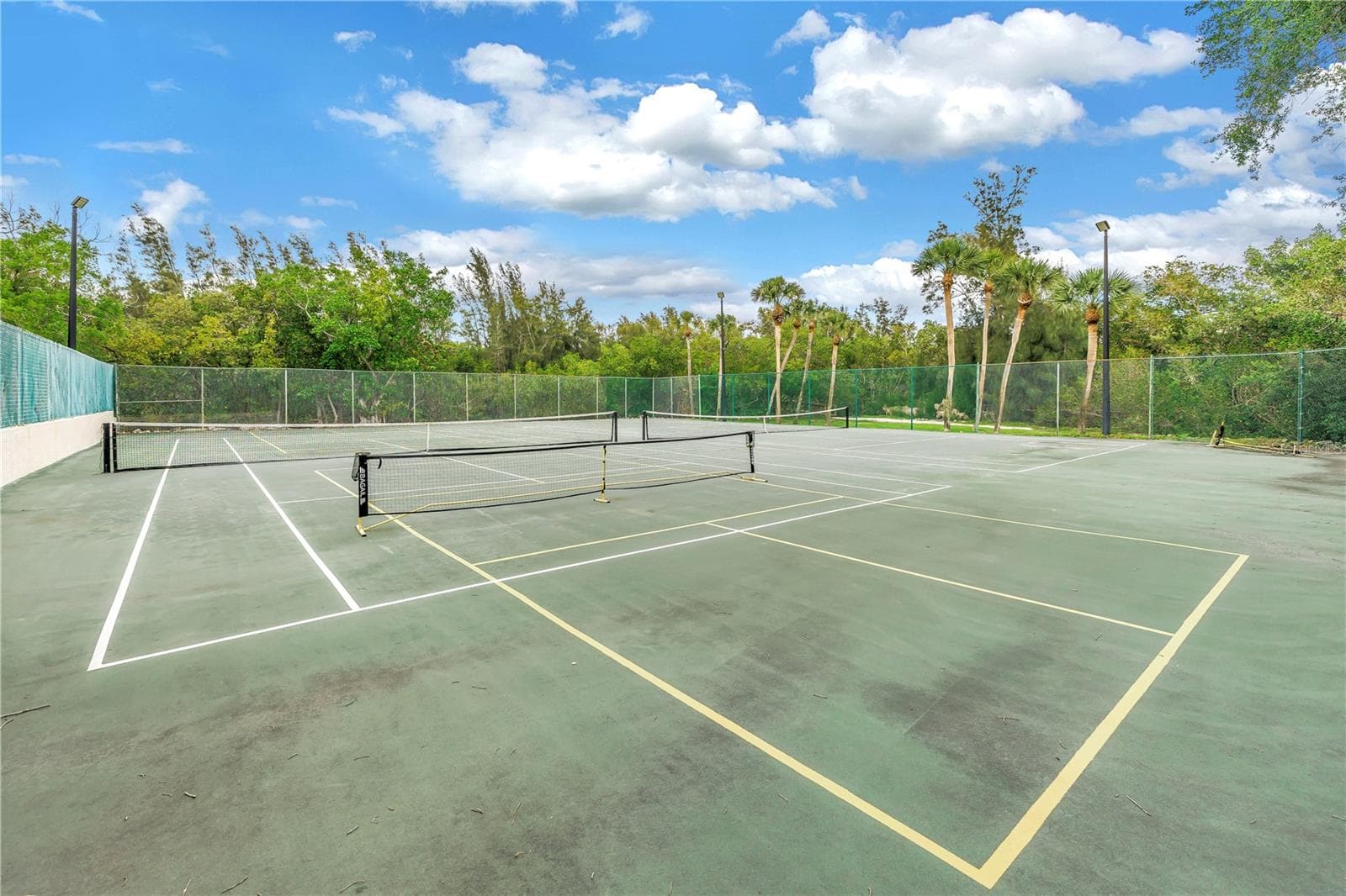 These two pickleball courts are easily accessible for day or night play and feature full lighting. The property also includes a tennis court. - 1186 GASPARILLA DR NE, ST PETERSBURG
