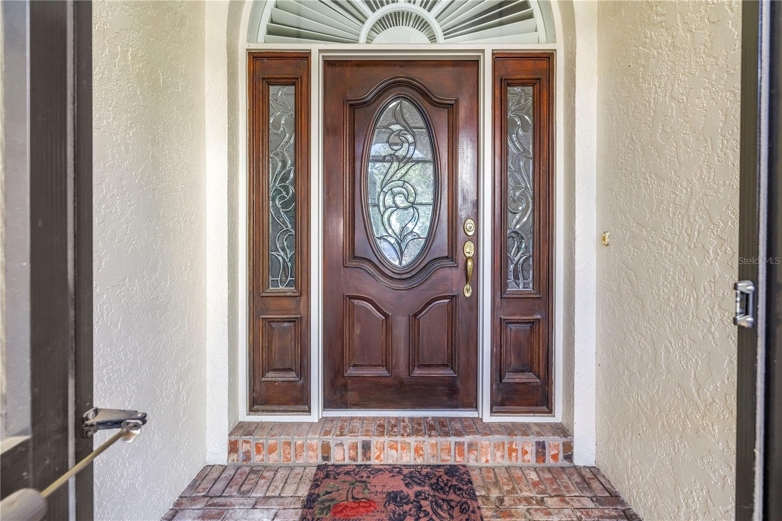 Beautiful front door featuring solid wood construction and elegant leaded glass. This upscale entry is also screened, allowing for refreshing natural breezes. - 1186 GASPARILLA DR NE, ST PETERSBURG