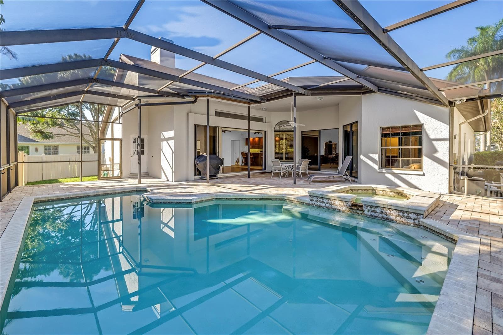 This backyard oasis features in-pool seating and expansive open space under the screened lanai. The design seamlessly integrates the interior living area with the outdoors while maintaining complete privacy. - 1186 GASPARILLA DR NE, ST PETERSBURG
