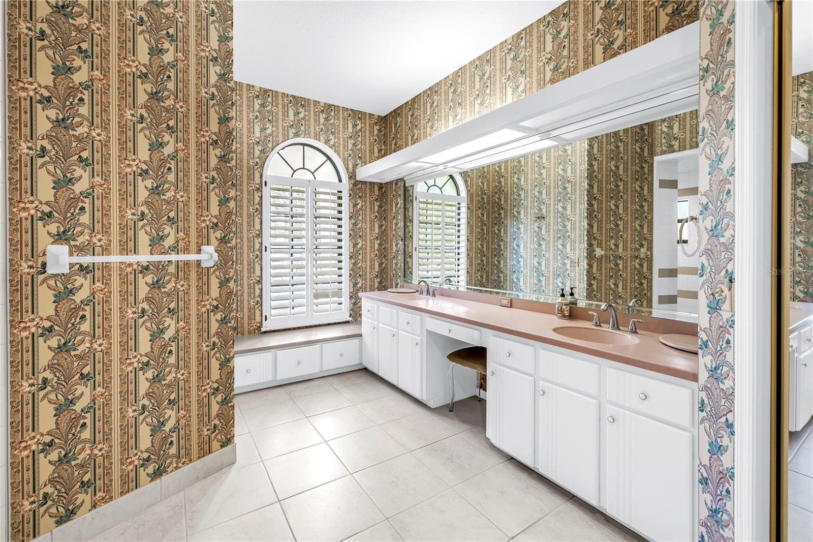 Current Photo of Primary Bath with long dual Vanity and dressing table. Shower is behind wall with towel bar. - 1186 GASPARILLA DR NE, ST PETERSBURG