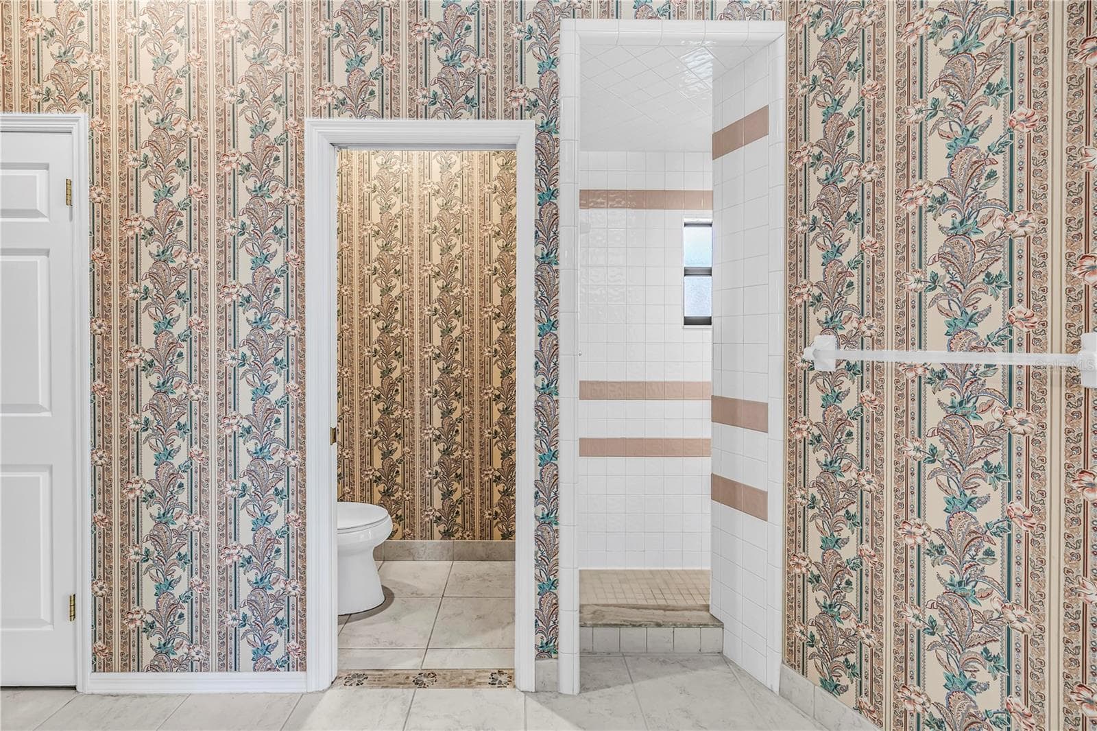 Current Photo of primary bathroom with toilet room and entry to shower. Again reference wall with towel bar for shower enclosure - 1186 GASPARILLA DR NE, ST PETERSBURG