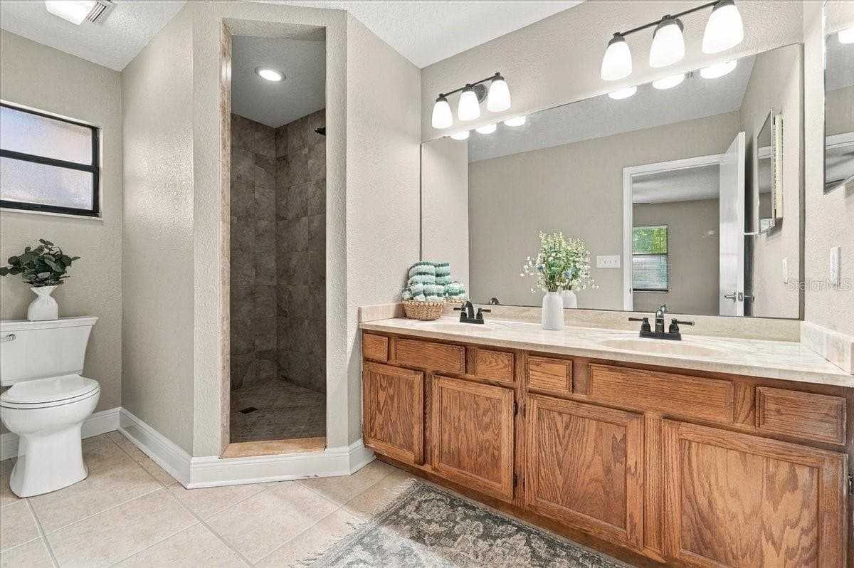 Primary Bath with Dual sinks, walk in shower, new toilet and cermic tile flooring. - 5244 QUIET CREEK LN, LAKELAND