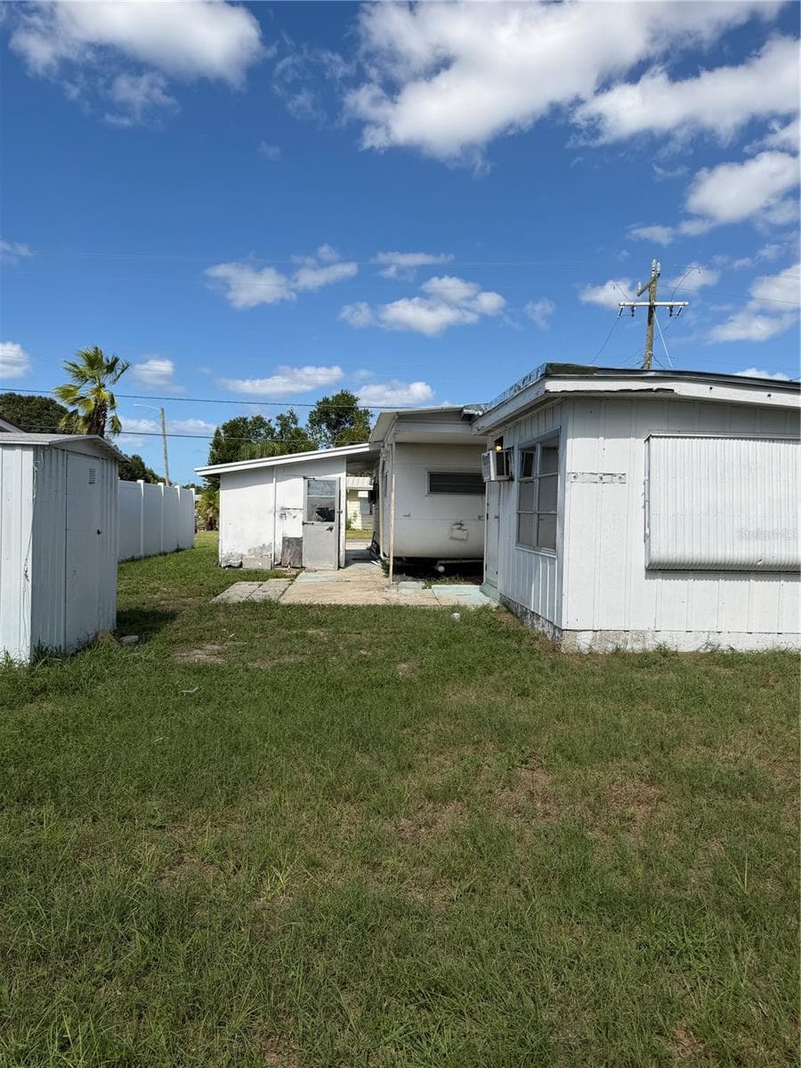 View of the fenced in backyard. Building on the left is storage and the laundry room is across from the main mobile. - 4120 BUENA VISTA LN, HOLIDAY