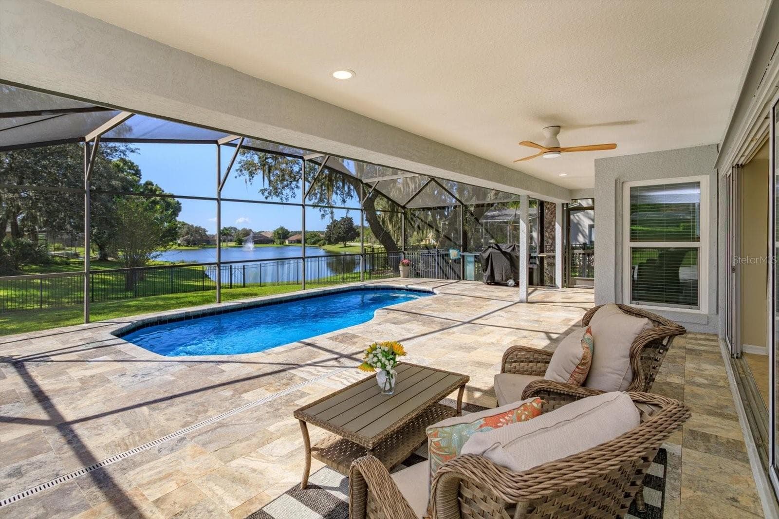 Travertine pavers on the covered porch and pool with sunset and water views - 6887 HIDDEN GLADE PL, SANFORD