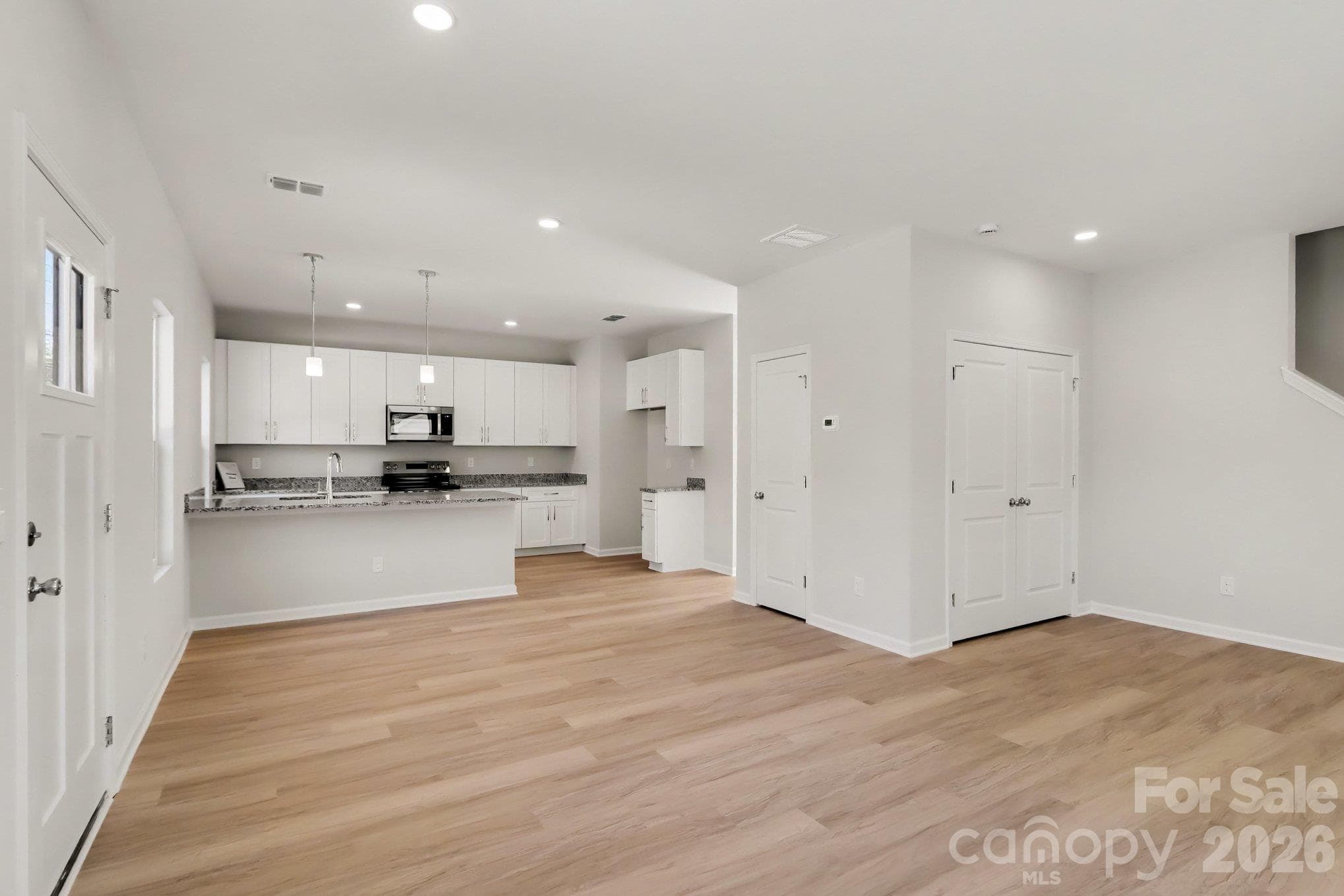 Great room & dining area. Kitchen has pantry. Great room has a storage closet. Half bath is also located on main level across from the office in the hallway leading to the back deck. Actual photo. - 125 Buffalo Avenue NW, Concord