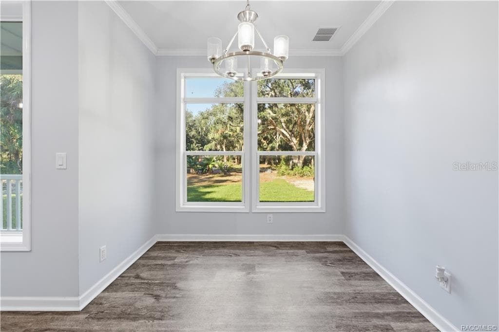 GATHER AROUND THE TABLE! The DINING AREA features a contemporary chandelier, attractive flooring & large windows framing views of the wooded property. - 7528 N CHABAUD TER, CRYSTAL RIVER