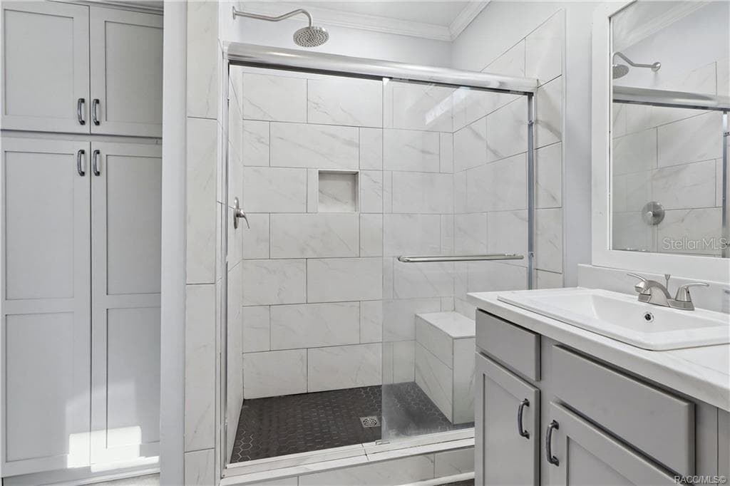 WALK-IN SHOWER features marble-look tile, a rainfall-style showerhead, glass sliding doors, built-in seating & a convenient recessed niche. - 7528 N CHABAUD TER, CRYSTAL RIVER