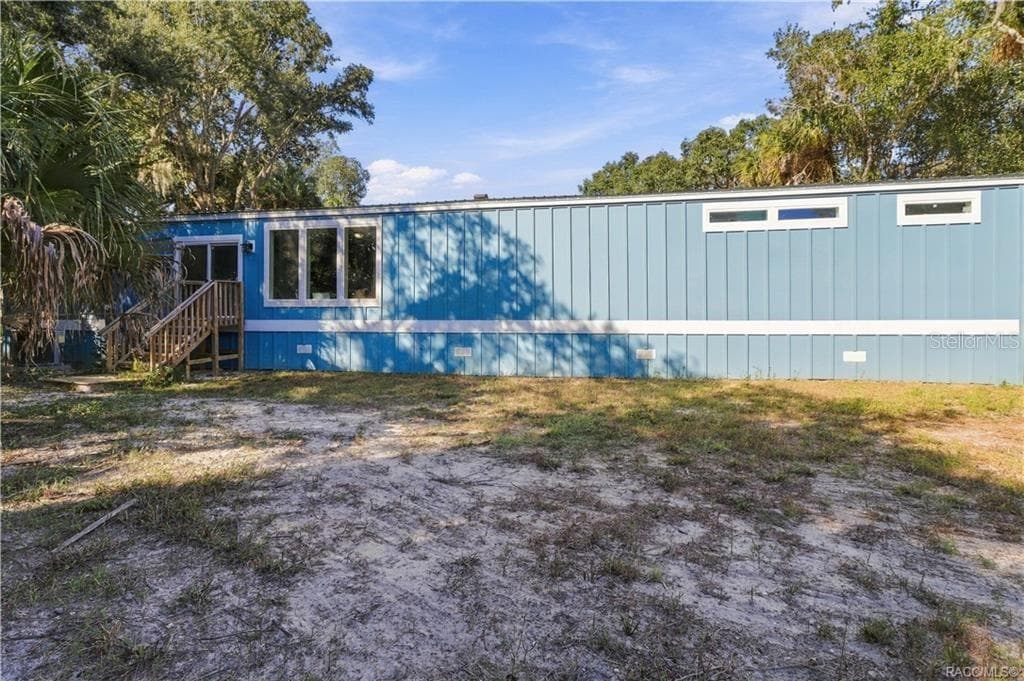 COUNTRY CHARM & ROOM TO ROAM! Another exterior view showcases the home's spacious setting, attractive siding, rear steps & surrounding greenery. - 7528 N CHABAUD TER, CRYSTAL RIVER