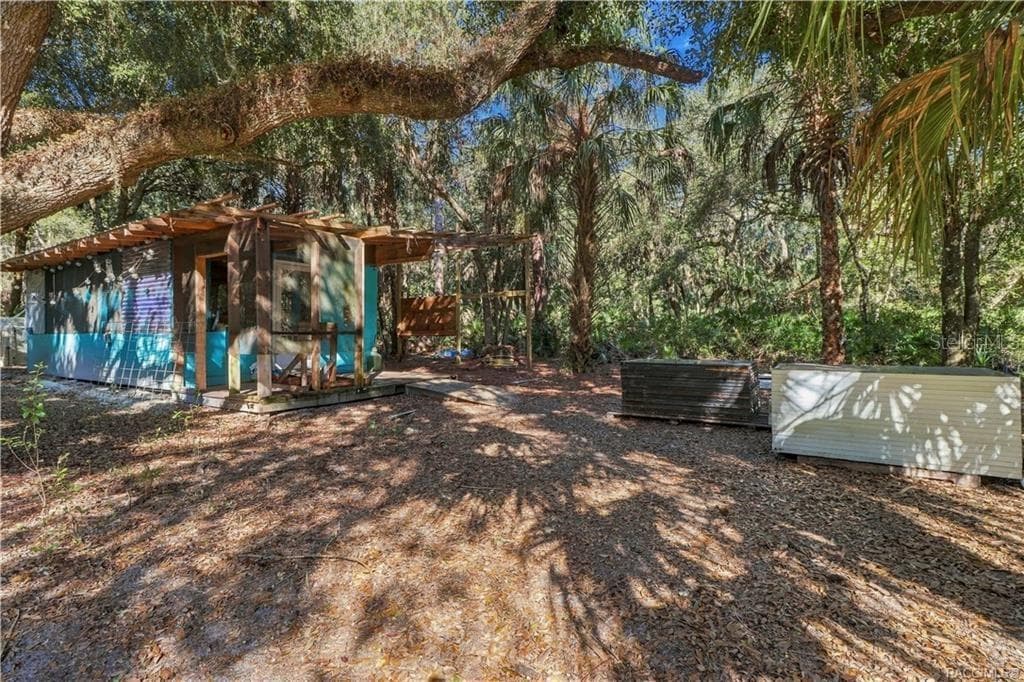 COUNTRY CHARACTER & OUTDOOR POSSIBILITIES! This rustic outbuilding features a covered wooden porch & adjoining open-air structure beneath the shade of mature trees. - 7528 N CHABAUD TER, CRYSTAL RIVER