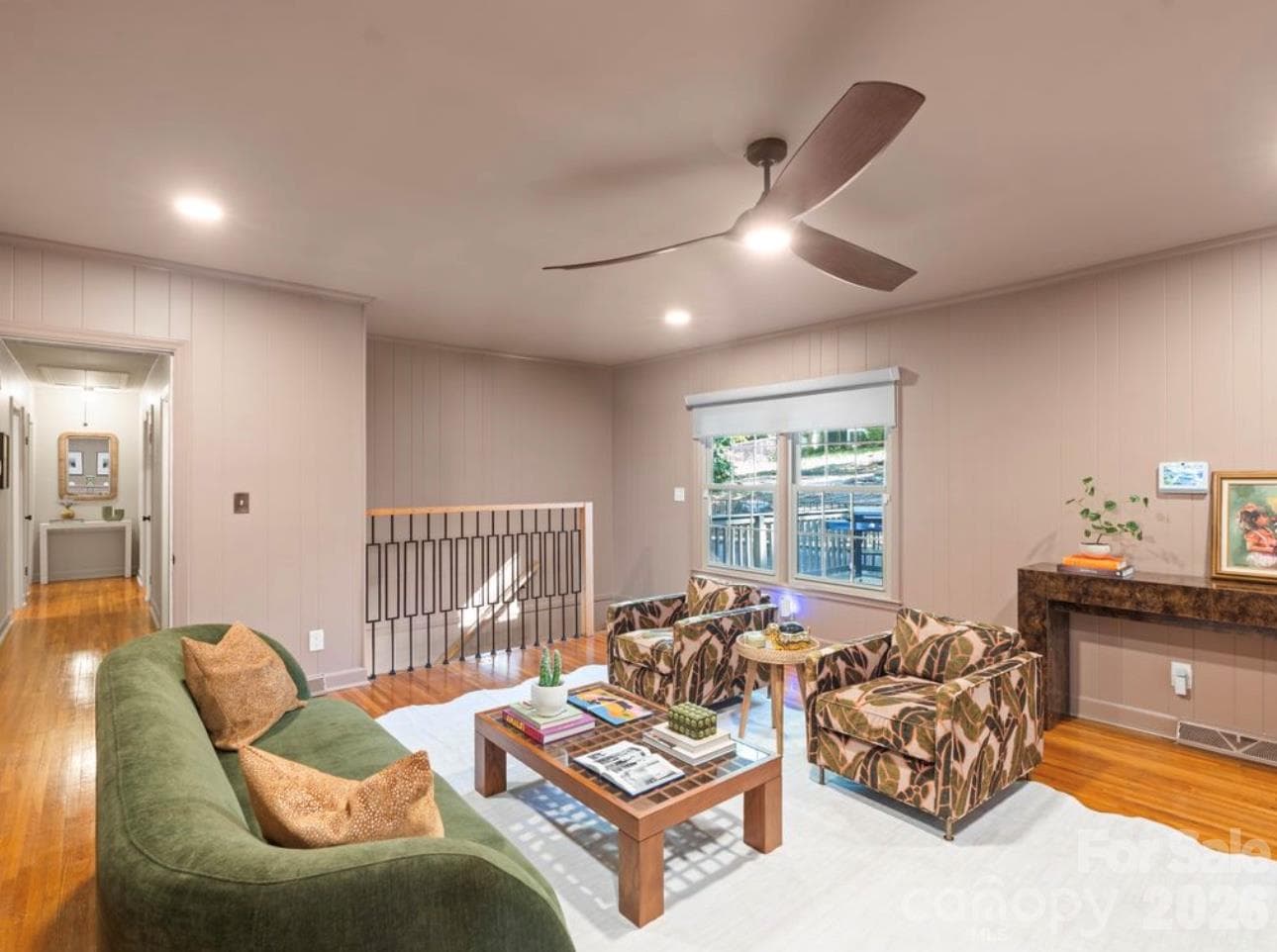 Living room just off the kitchen features a new stair railing, and beautiful hardwood floors. The doorway leads down the hall for access to the main level bedrooms and hall full bath - 6626 Rocky Falls Road, Charlotte
