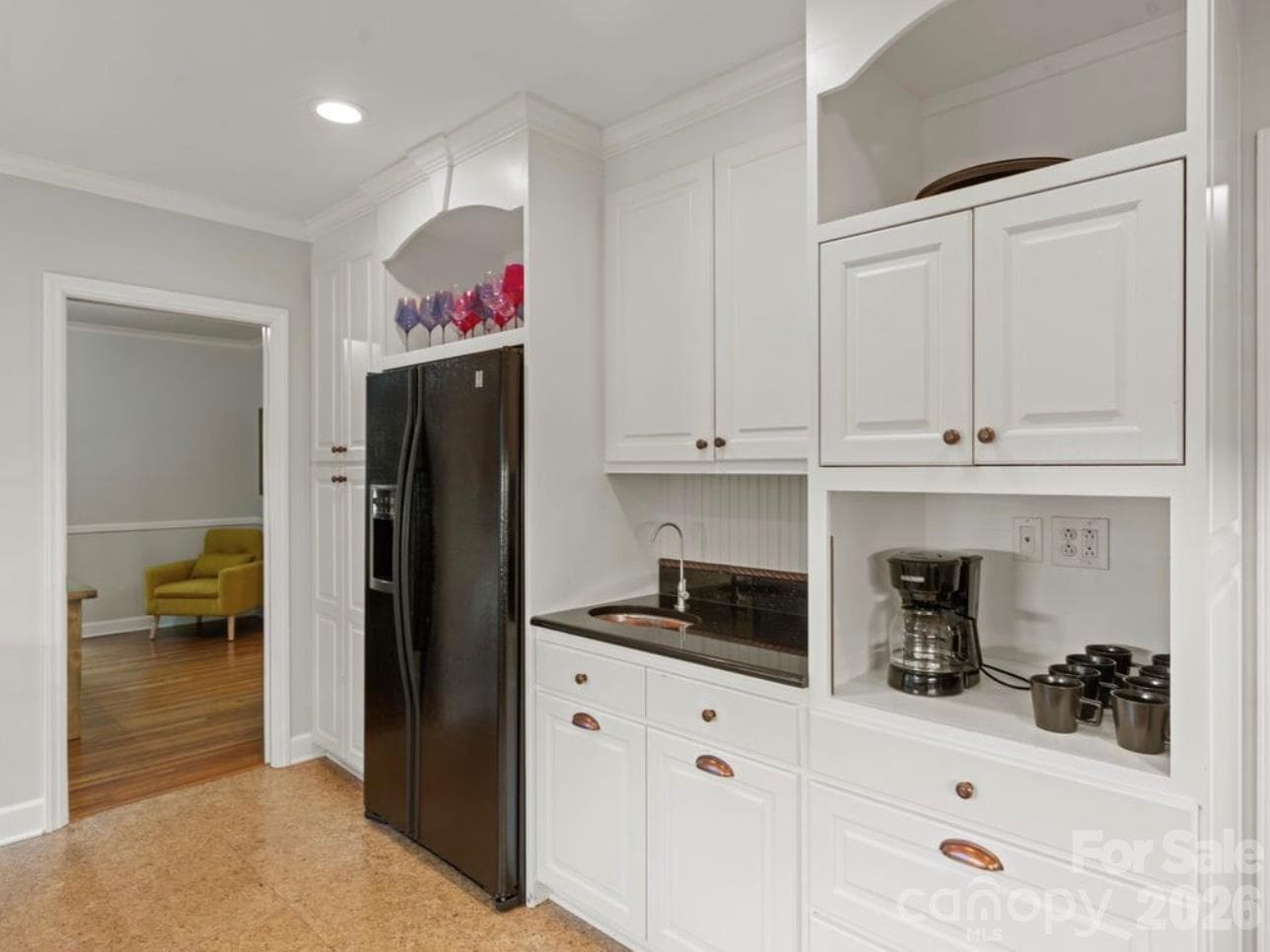 Abundant cabinetry provides excellent storage, while a dedicated coffee bar and beverage area with a distinctive hammered copper beverage sink add character and functionality. Dining room just off the kitchen. - 6626 Rocky Falls Road, Charlotte