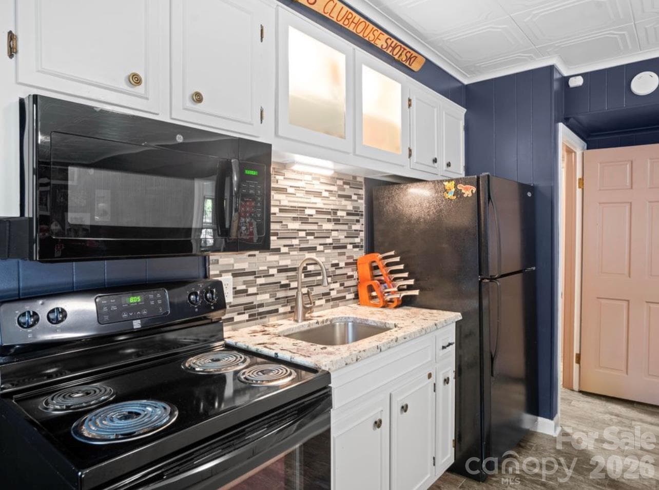 Discover the convenience of a beautifully appointed second kitchen in the basement, featuring sleek black appliances, elegant granite countertops, updated cabinetry, and a stylish backsplash. - 6626 Rocky Falls Road, Charlotte