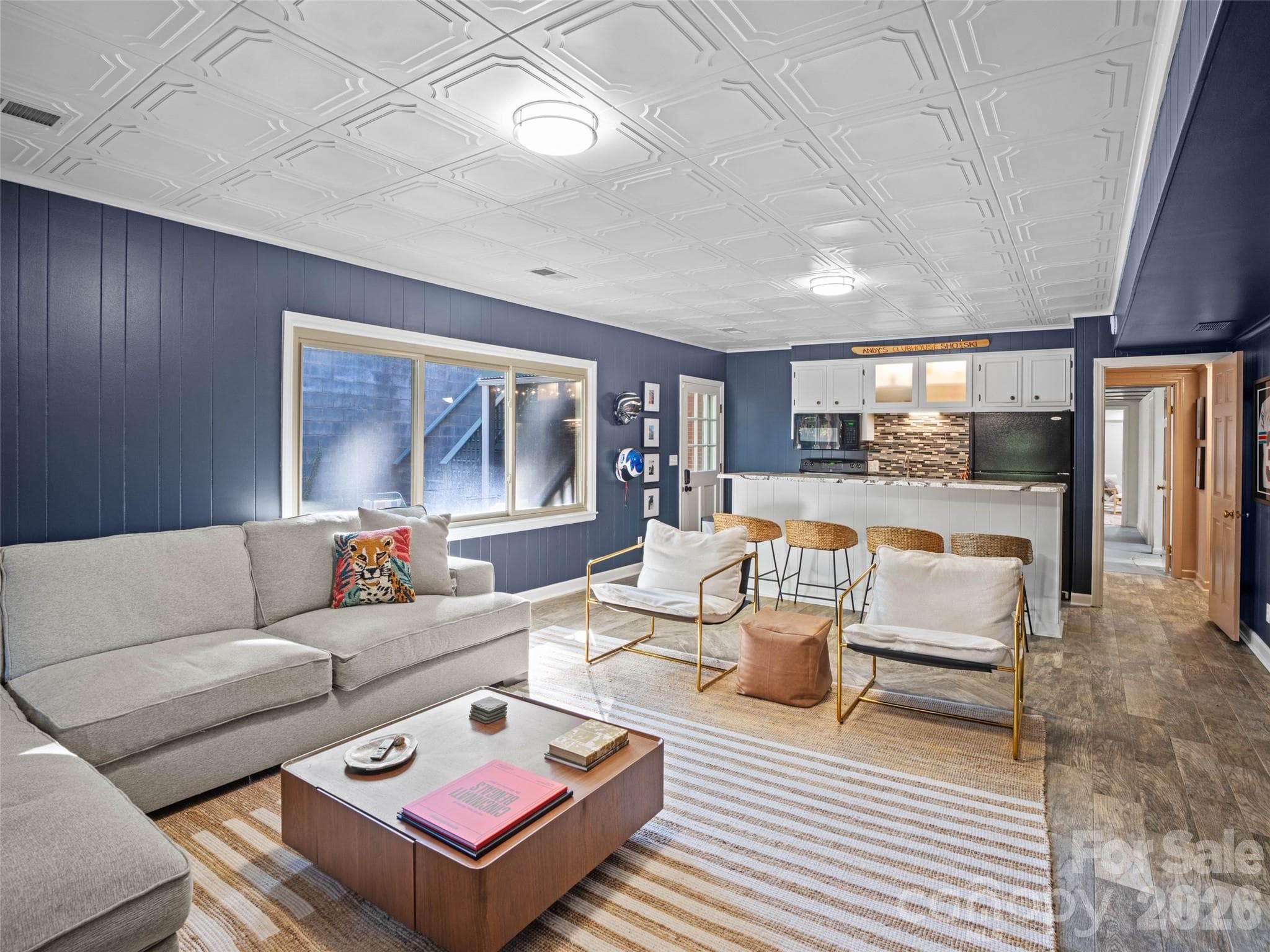Another view of the spacious, open-concept lower-level living area showcases the versatility and flow of this additional living space. The door near the kitchen provides direct access to the patio, making indoor-outdoor entertaining a breeze, while the door to the right leads to a partially finished, heated flex spaces in the basement. - 6626 Rocky Falls Road, Charlotte