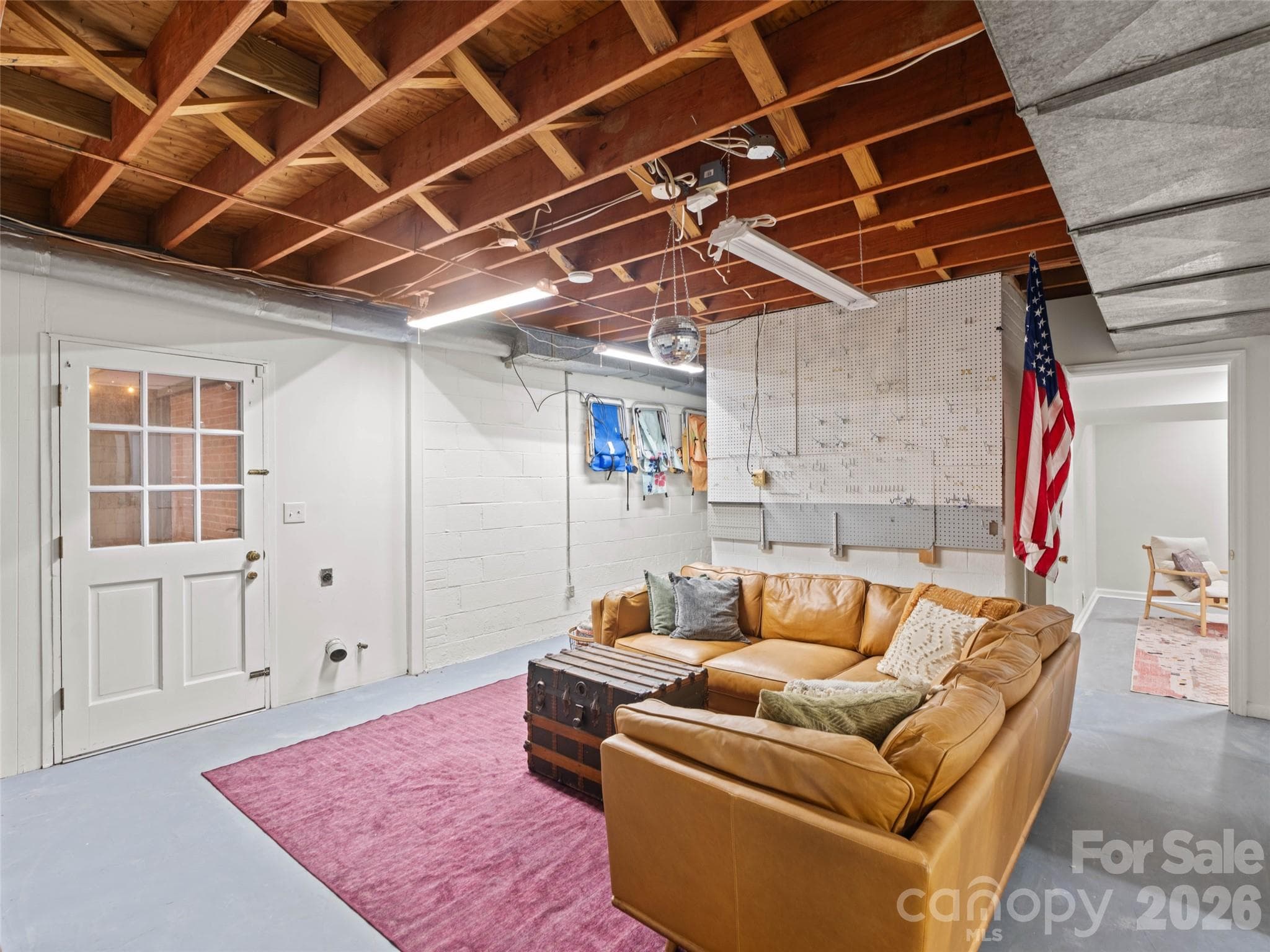 The possibilities are endless in this  heated and cooled basement flex space! While this space is NOT included in the home’s official heated living area (HLA), it is currently showcased as a fun hangout area. This versatile space could easily be transformed into a media room, playroom, hobby area, or additional storage. The door shown provides convenient access to the covered patio, extending your options for relaxation and entertaining. - 6626 Rocky Falls Road, Charlotte