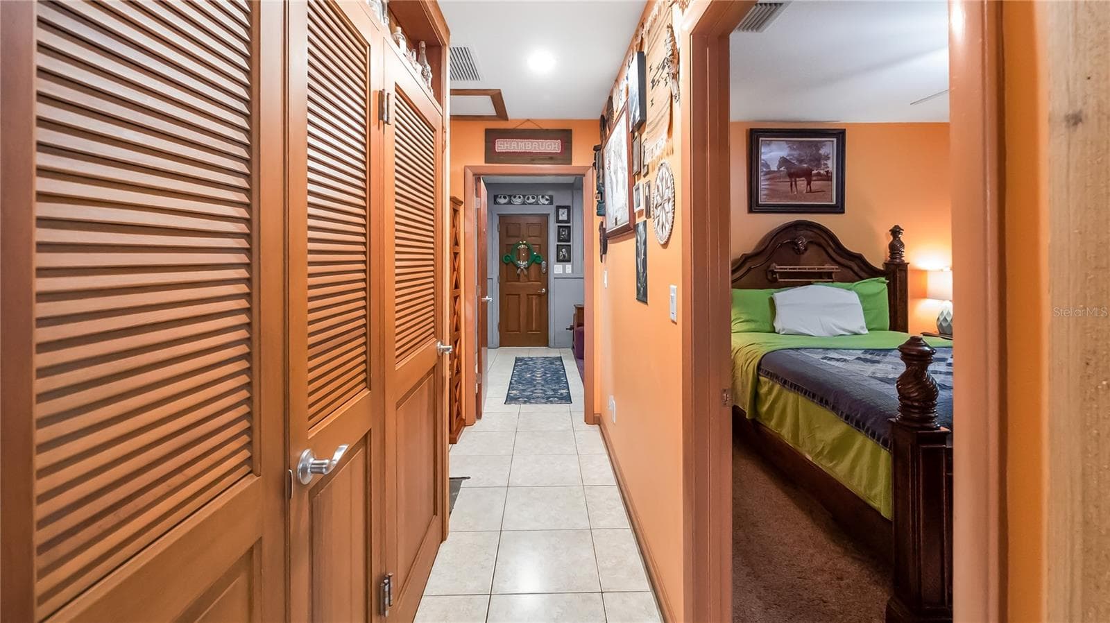 Hall way on guest north side of the main home. Two bedrooms (one being used as TV room, Full bathroom and laundry room. wall of storage closets that lead to an exit door to pool. Easiy access to guest bathroom from pool. - 1730 NITA PL, CLERMONT