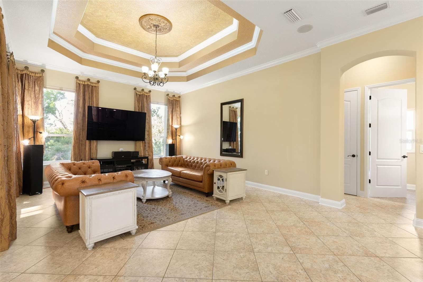 An elegant gathering room where a dramatic tray ceiling, crown molding and decorative lighting create a beautiful setting for relaxing and entertaining. - 25 EMERALD LAKE CT, PALM COAST