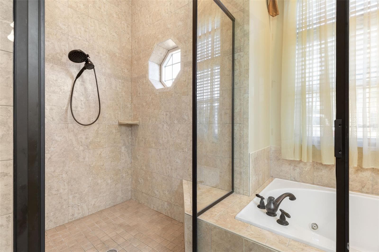 A spacious, tiled walk-in shower featuring glass enclosure, handheld showerhead, and a distinctive octagonal window. - 25 EMERALD LAKE CT, PALM COAST