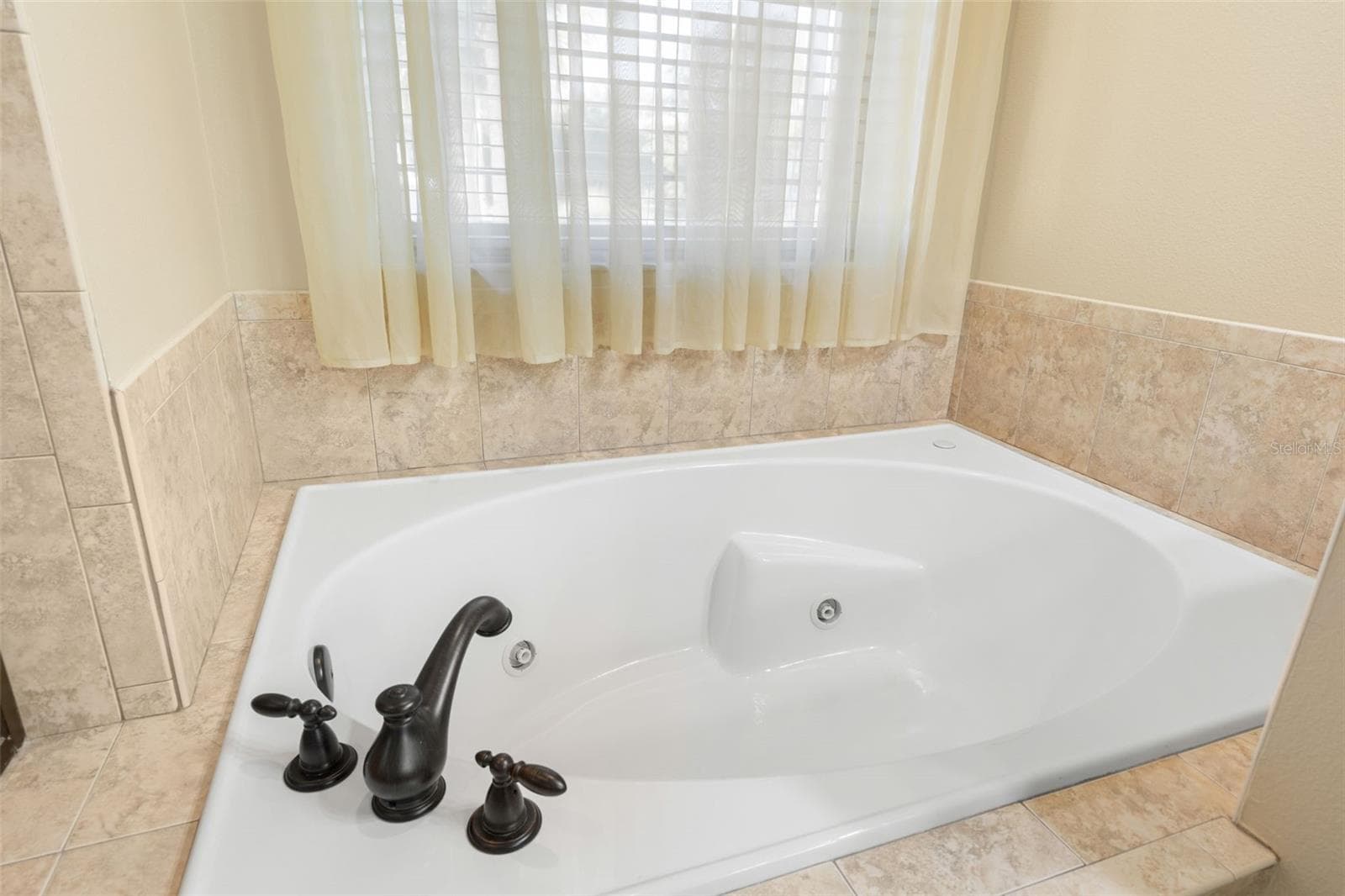 Unwind in the generously sized soaking tub, positioned beneath a window that brings soft natural light into the space. - 25 EMERALD LAKE CT, PALM COAST