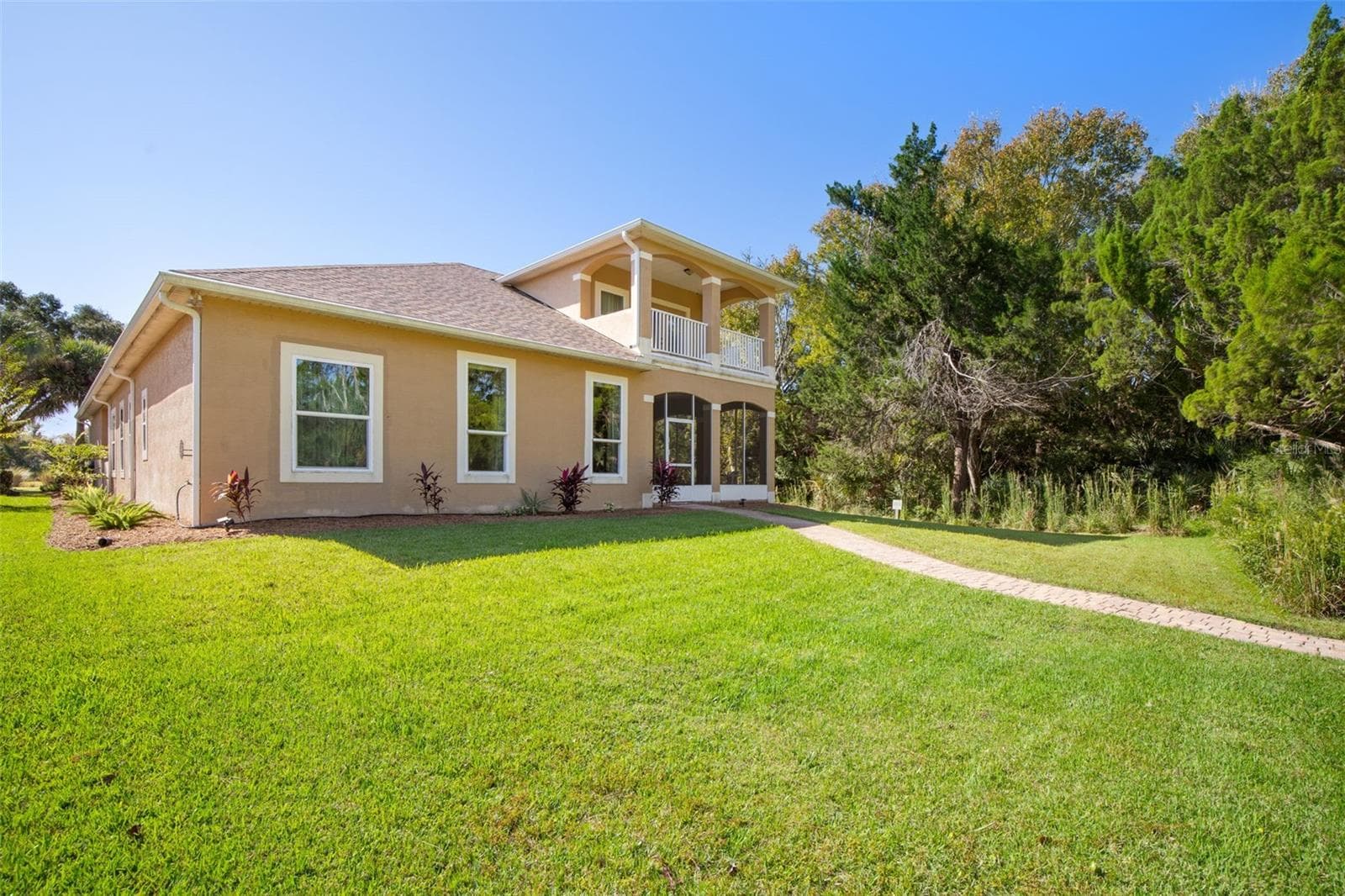 Rear exterior featuring a private upstairs balcony, screened lanai, and spacious backyard. - 25 EMERALD LAKE CT, PALM COAST