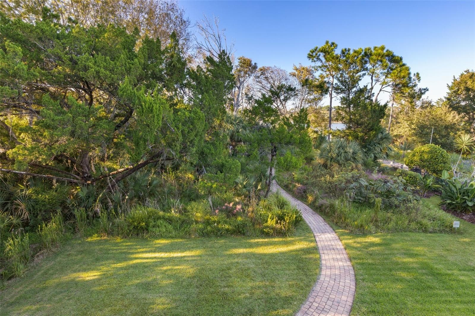 Winding paver walkway through natural greenery leading toward Emerald Lake. - 25 EMERALD LAKE CT, PALM COAST