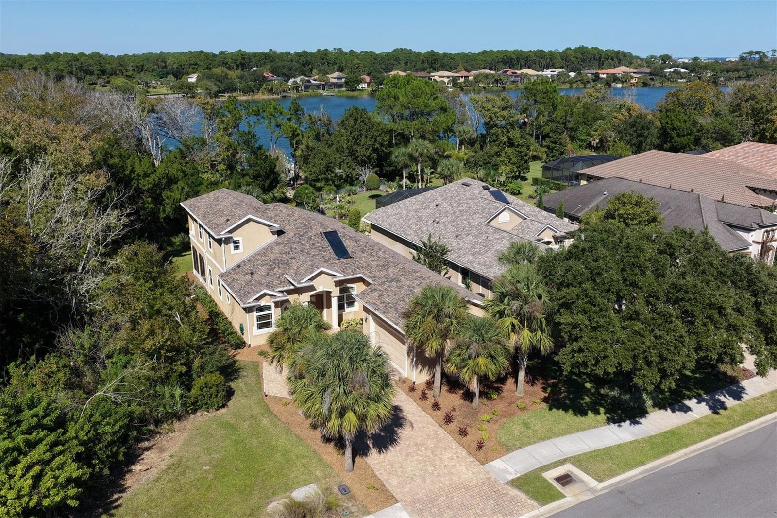 Distinctive architectural design, lush landscaping, and a paver driveway, with Emerald Lake providing a beautiful backdrop to this Palm Coast Plantation home. - 25 EMERALD LAKE CT, PALM COAST