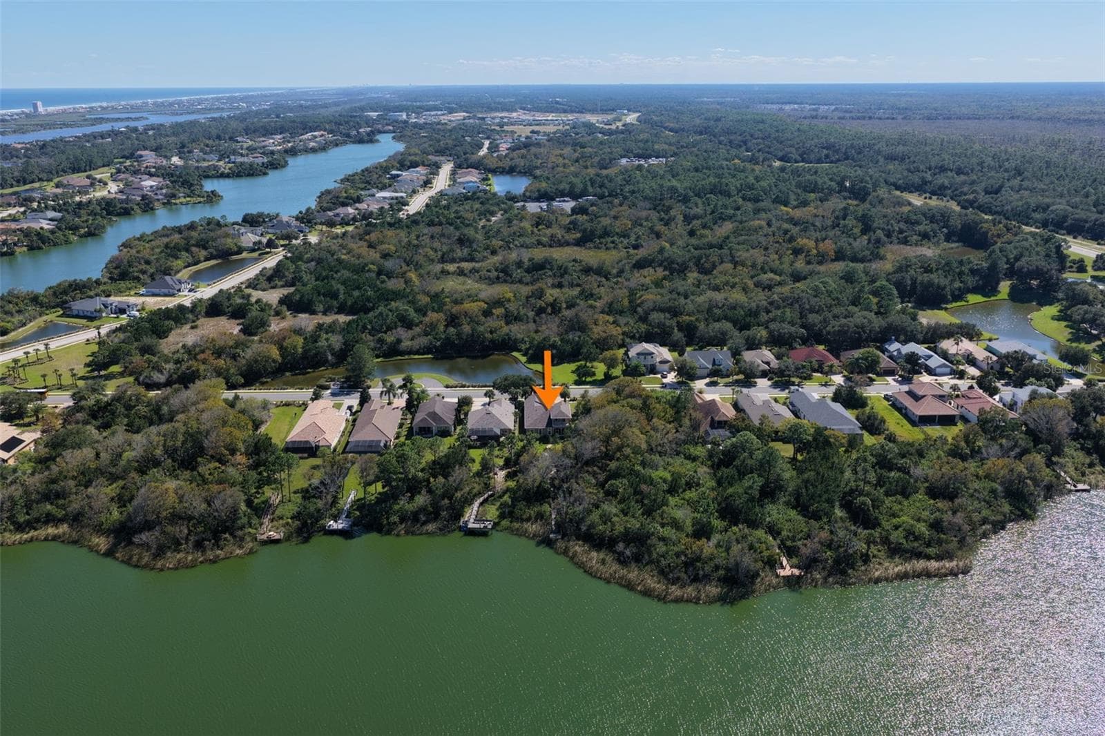 Aerial perspective showcasing the home's location along Emerald Lake, surrounded by natural greenery within Palm Coast Plantation. - 25 EMERALD LAKE CT, PALM COAST