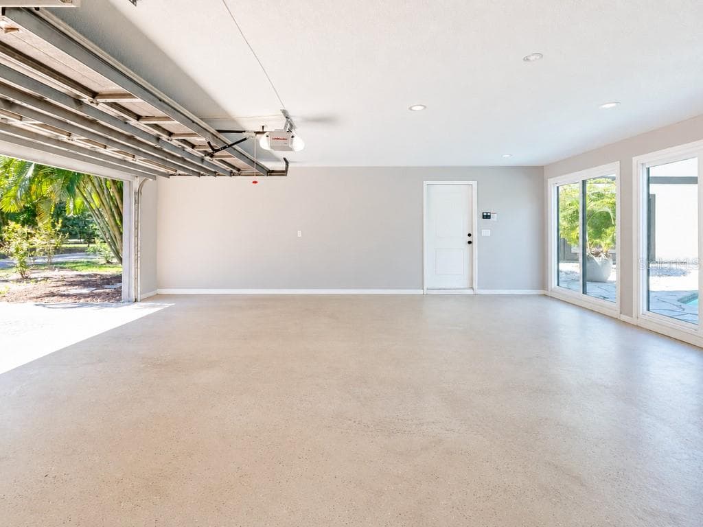 Expansive three-car garage offering exceptional space, with multiple glass doors providing natural light and convenient access toward the pool area - 403 LONGBOW TRL, OSPREY