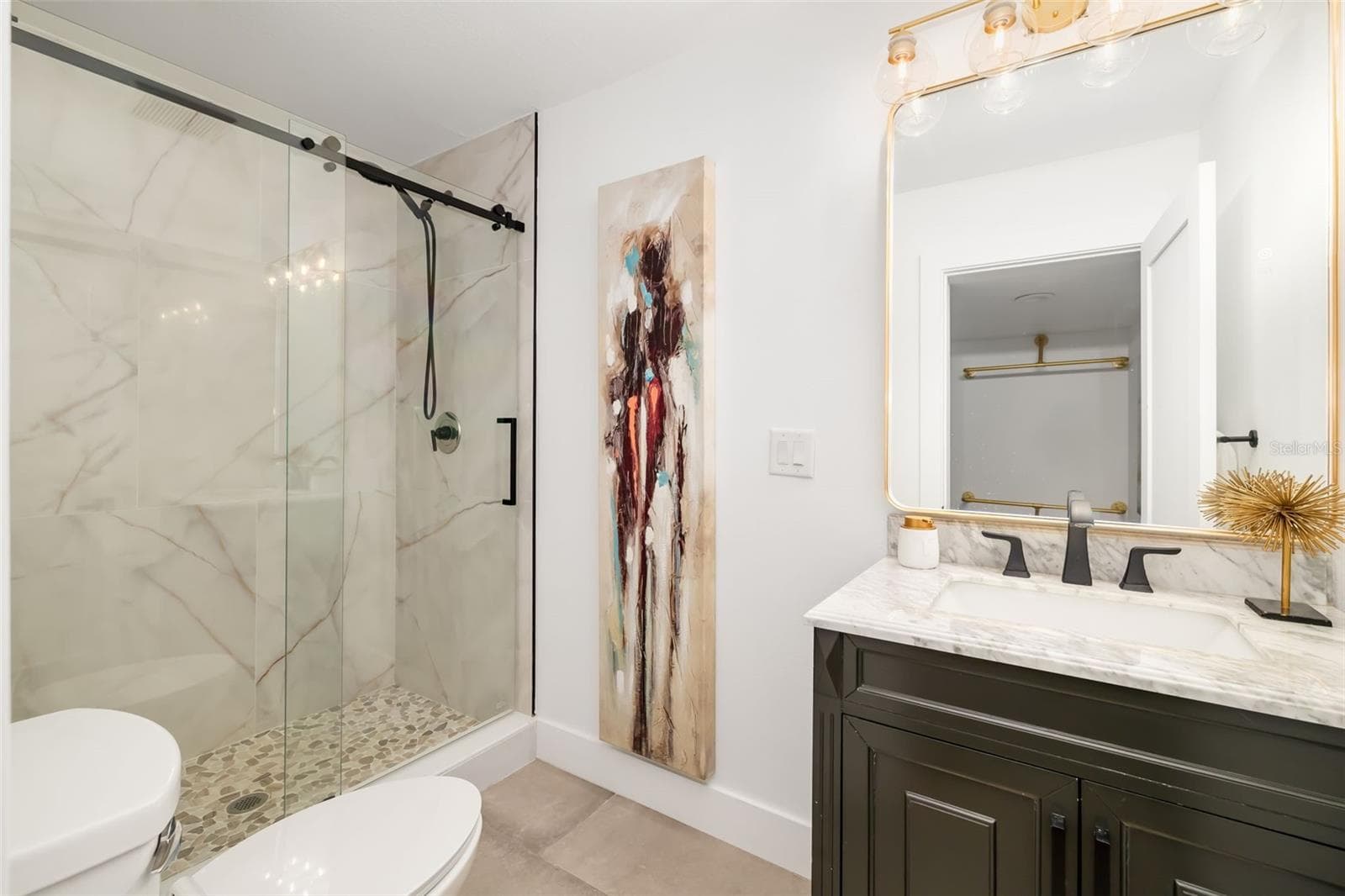 Full bath serving the additional bedroom and living area, featuring a glass-enclosed shower and updated finishes. - 403 LONGBOW TRL, OSPREY