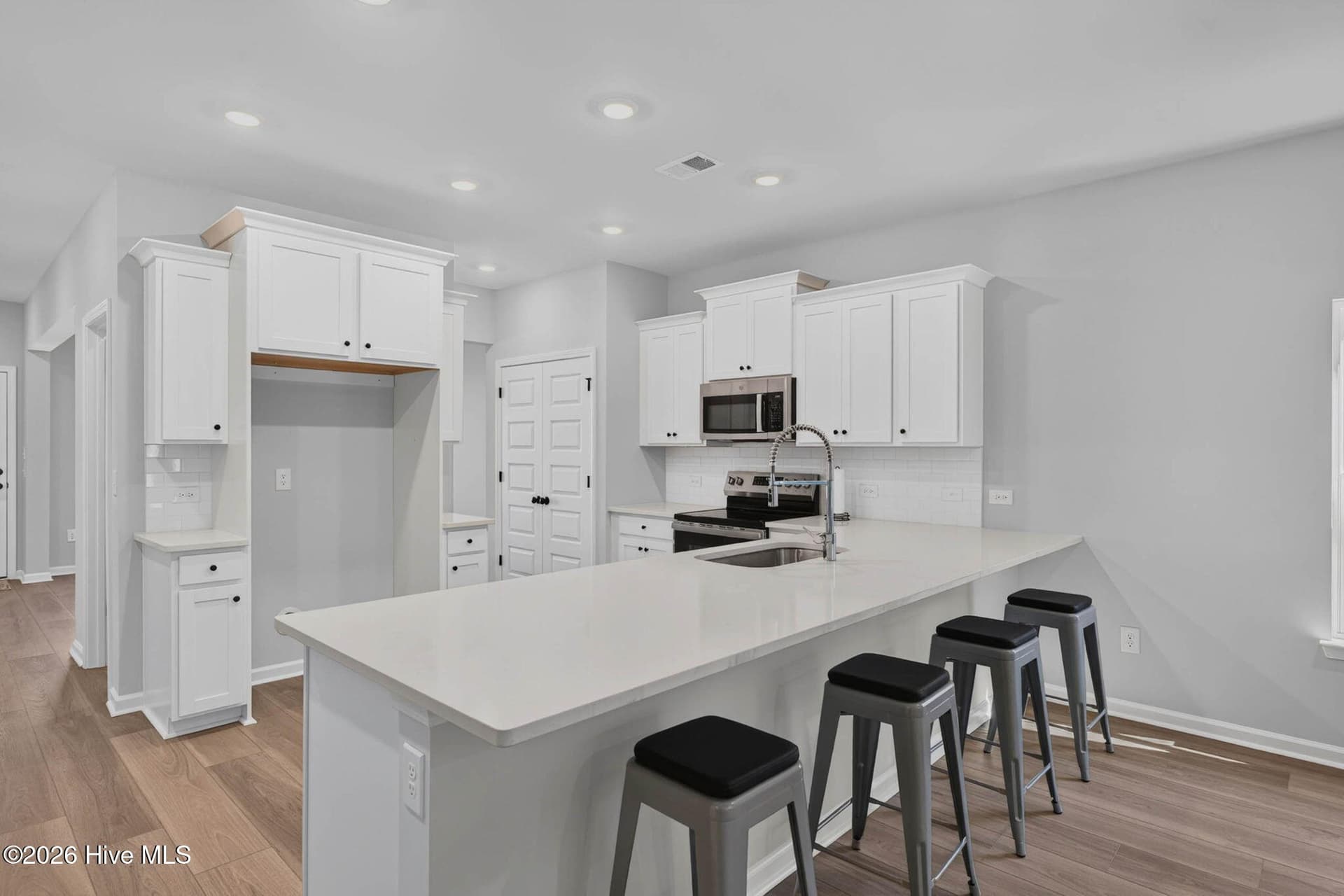 Bright coastal kitchen with quartz countertops, white cabinetry, island seating, and an open-concept design. - 3447 Sandhill Crane Drive SW, Ocean Isle Beach, NC 28469